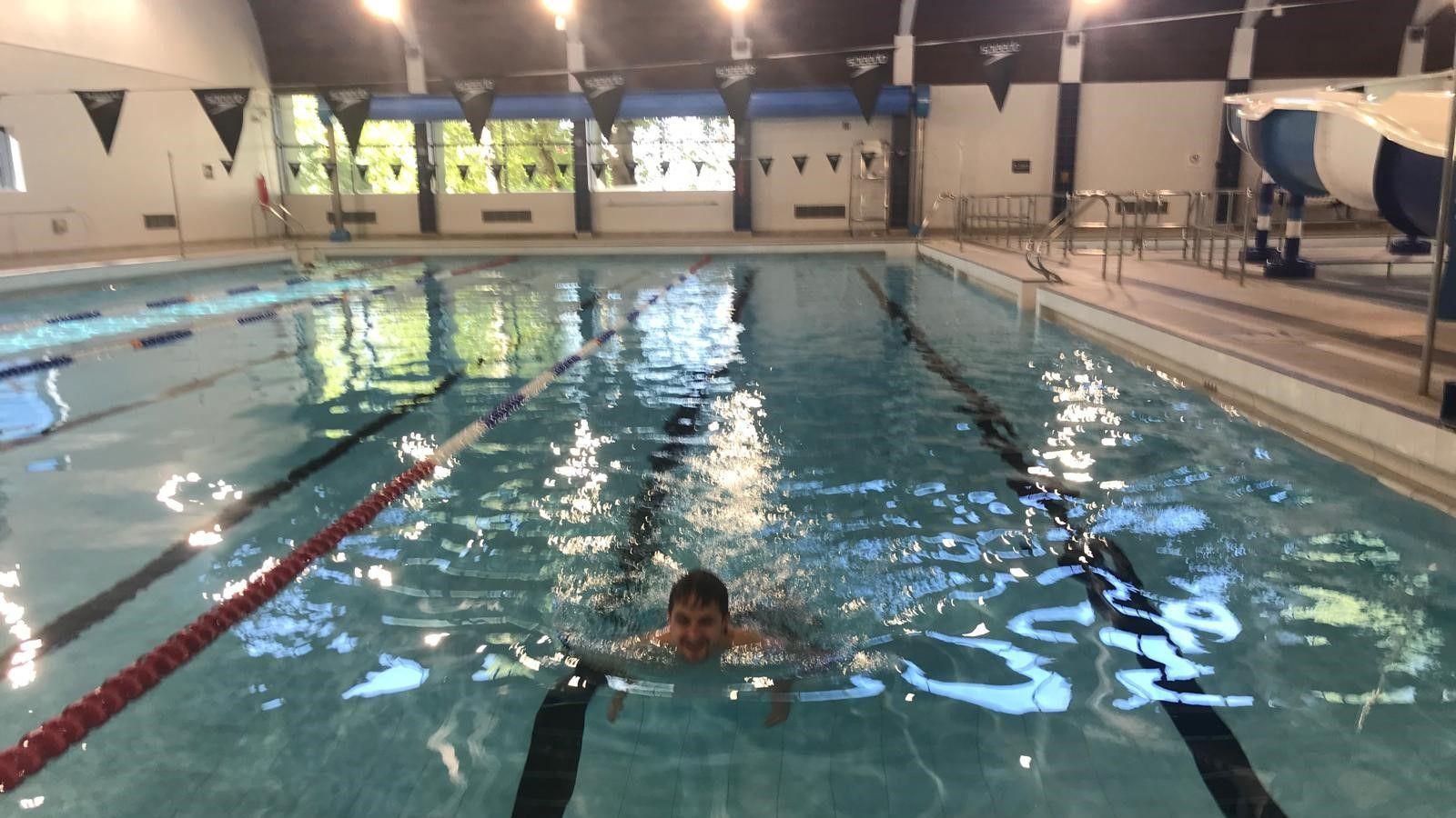 A man swimming in Birtley Pool. The pool has several lanes and there are small triangular flags hanging over the pool.