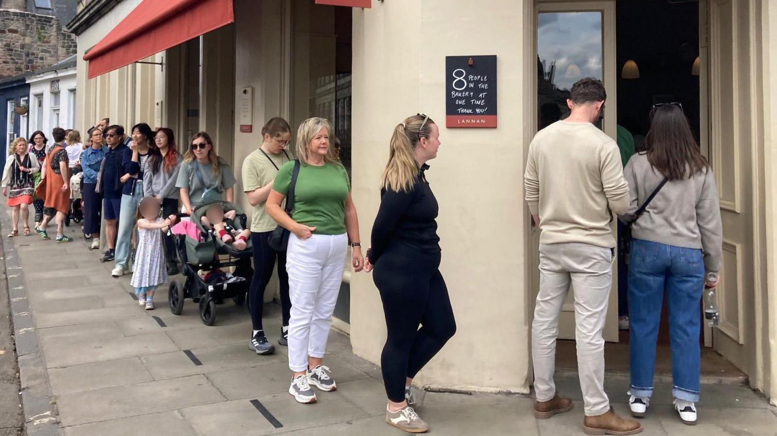 A large queue snakes down the street outside the bakery.