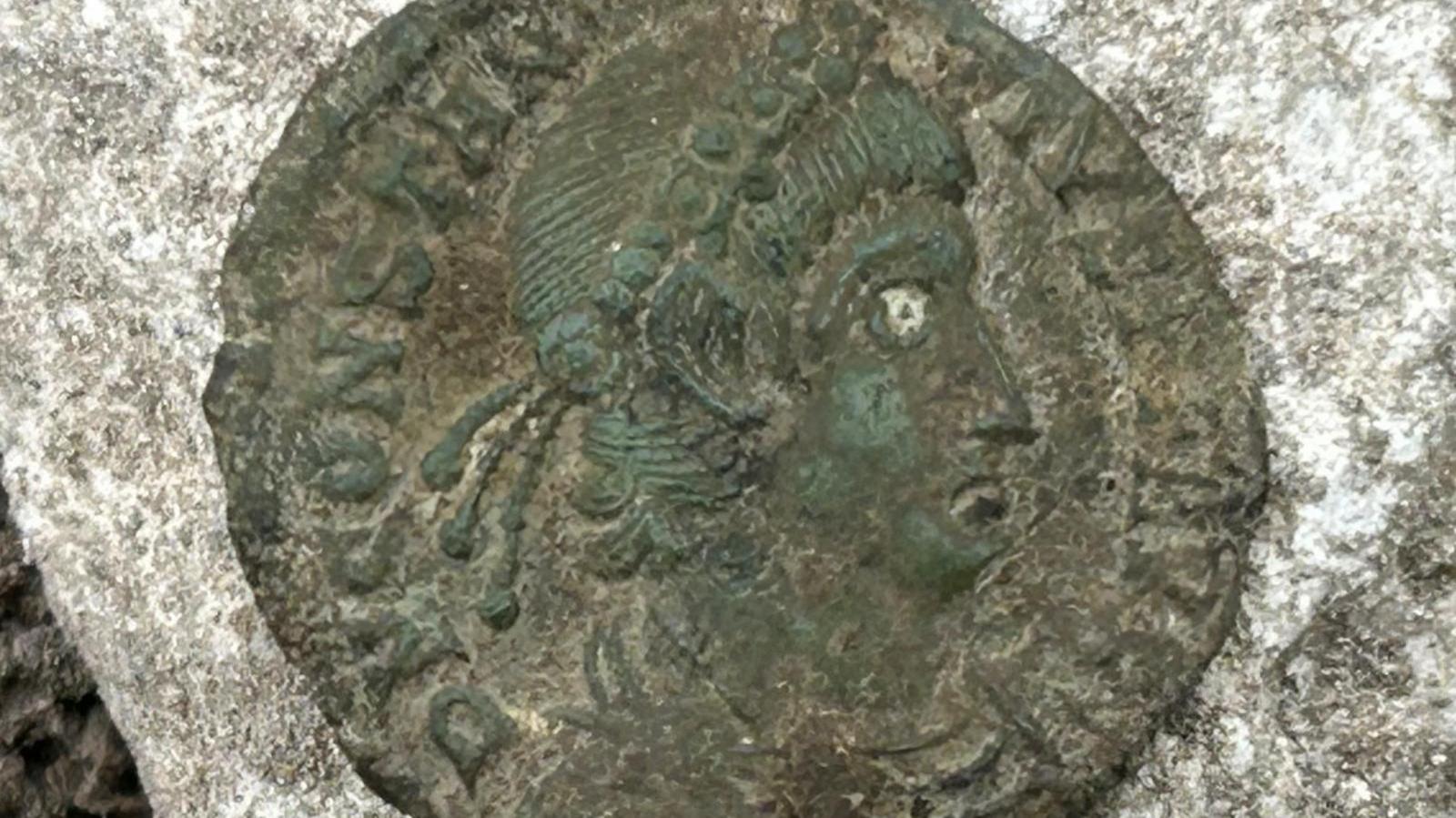 A Roman coin, with the face of a late emperor stamped on it.