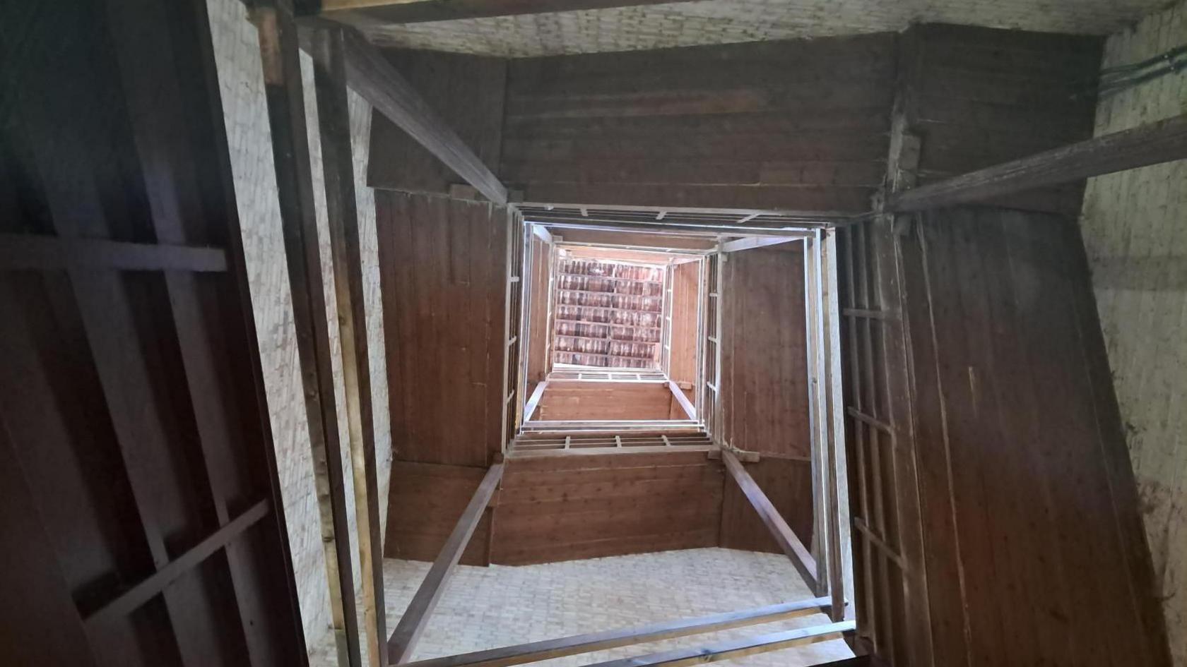 A wooden staircase winds around the inside of a stone tower.