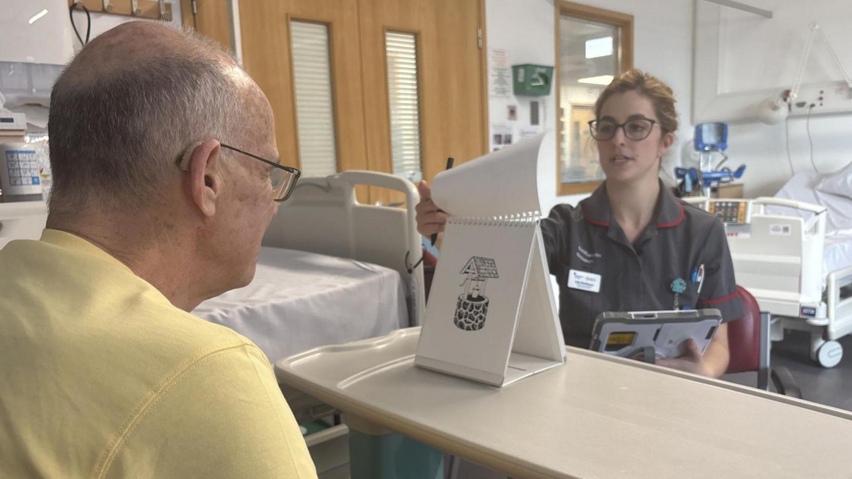 A Dementia Research Nurse turns a flip chart of images for a clinical trial participant to identify.
