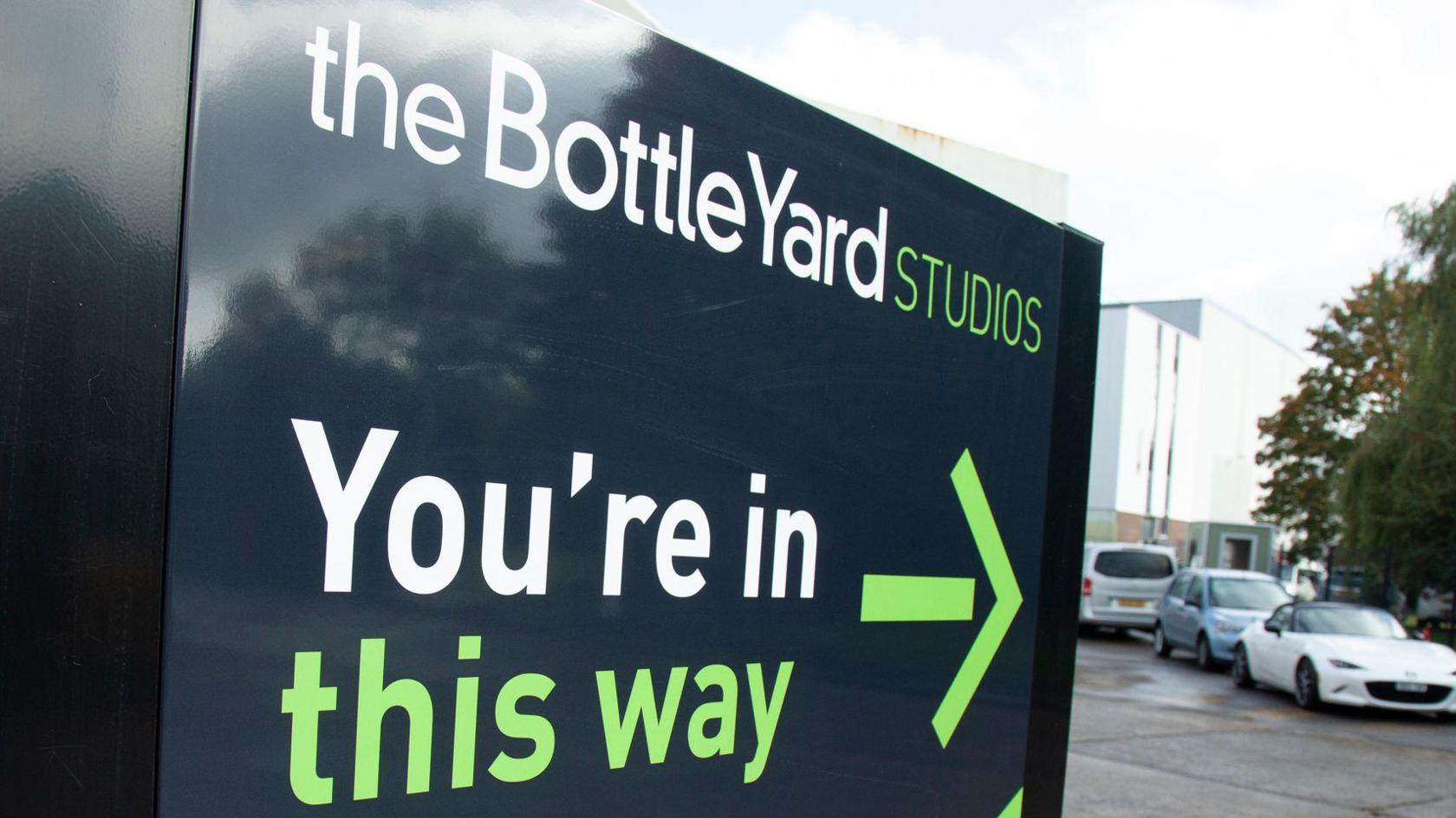 The sign outside the entrance to the studios. It says The Bottle Yard Studios, You're in, this way and has an arrow pointing inwards