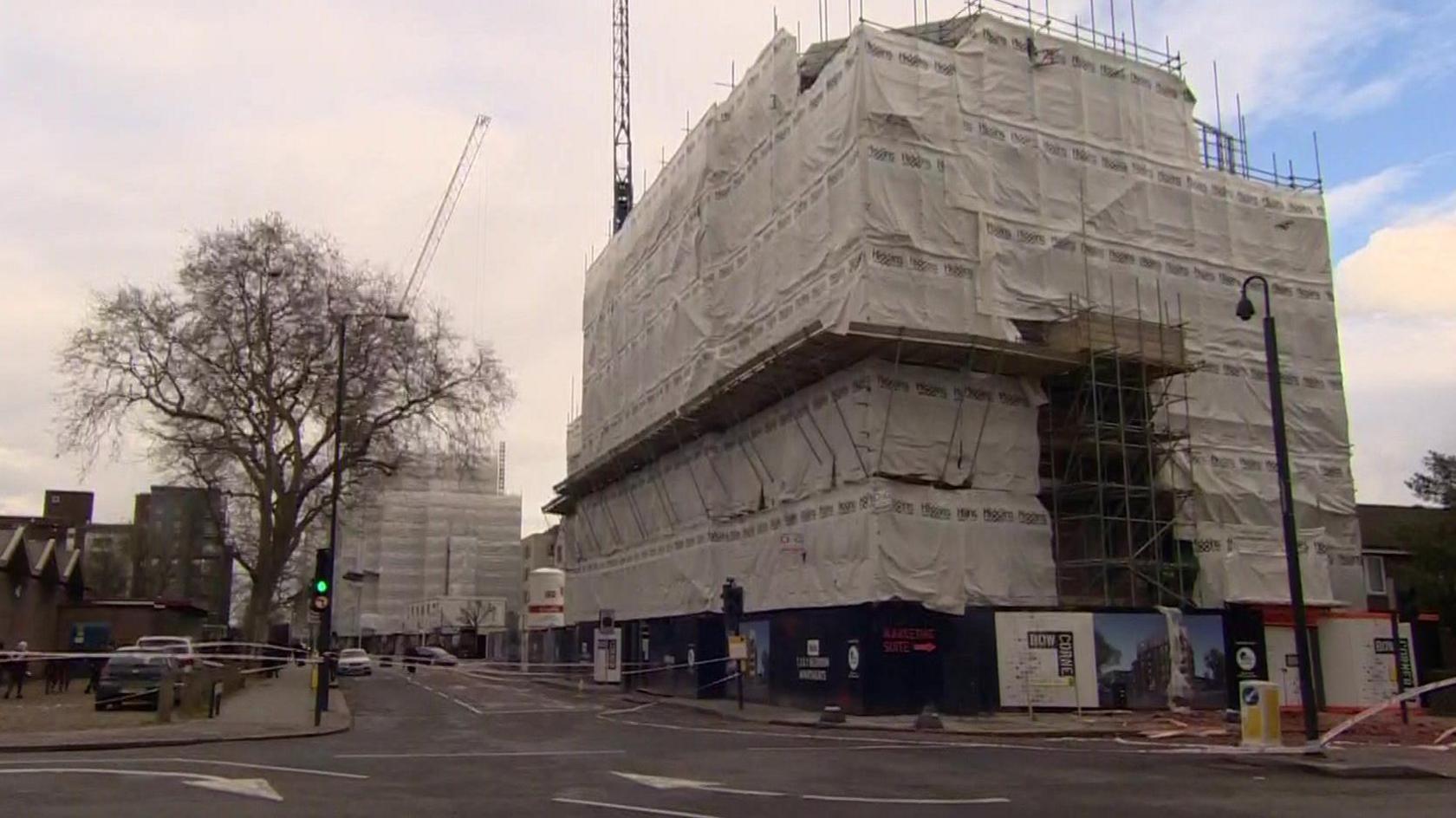 Two large buildings covered in tarpaulin and scaffolding - the building site where the accident happened.