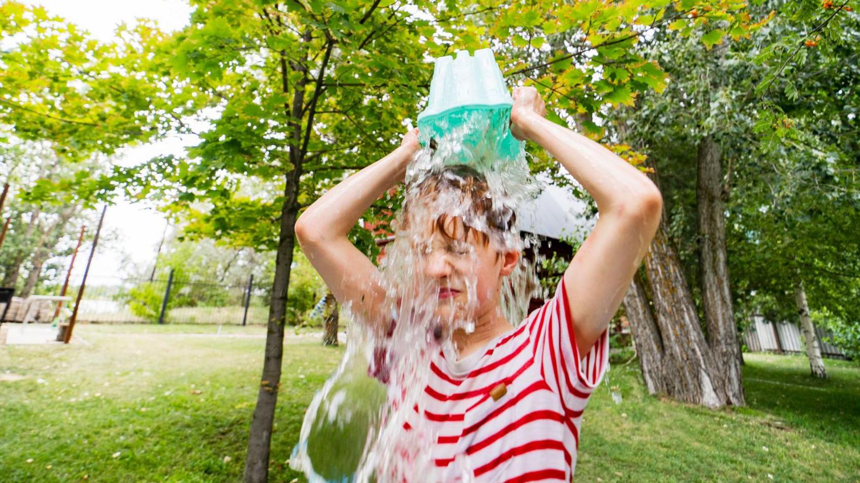 child pouring bucket of water over their head