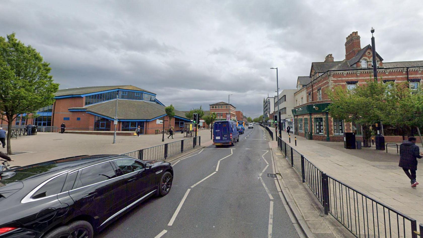 A general view of Hartlepool town centre. Cars drive down a grey tarmac with red brick buildings on either side.