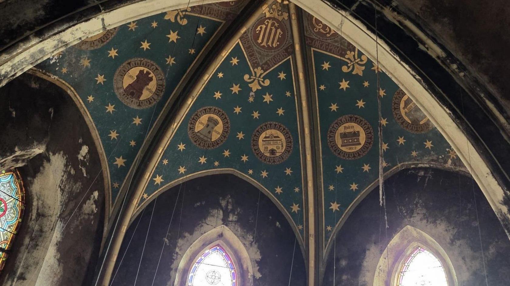 The ceiling of the former monastery in Paignton. There is art on the ceiling and windows below it.