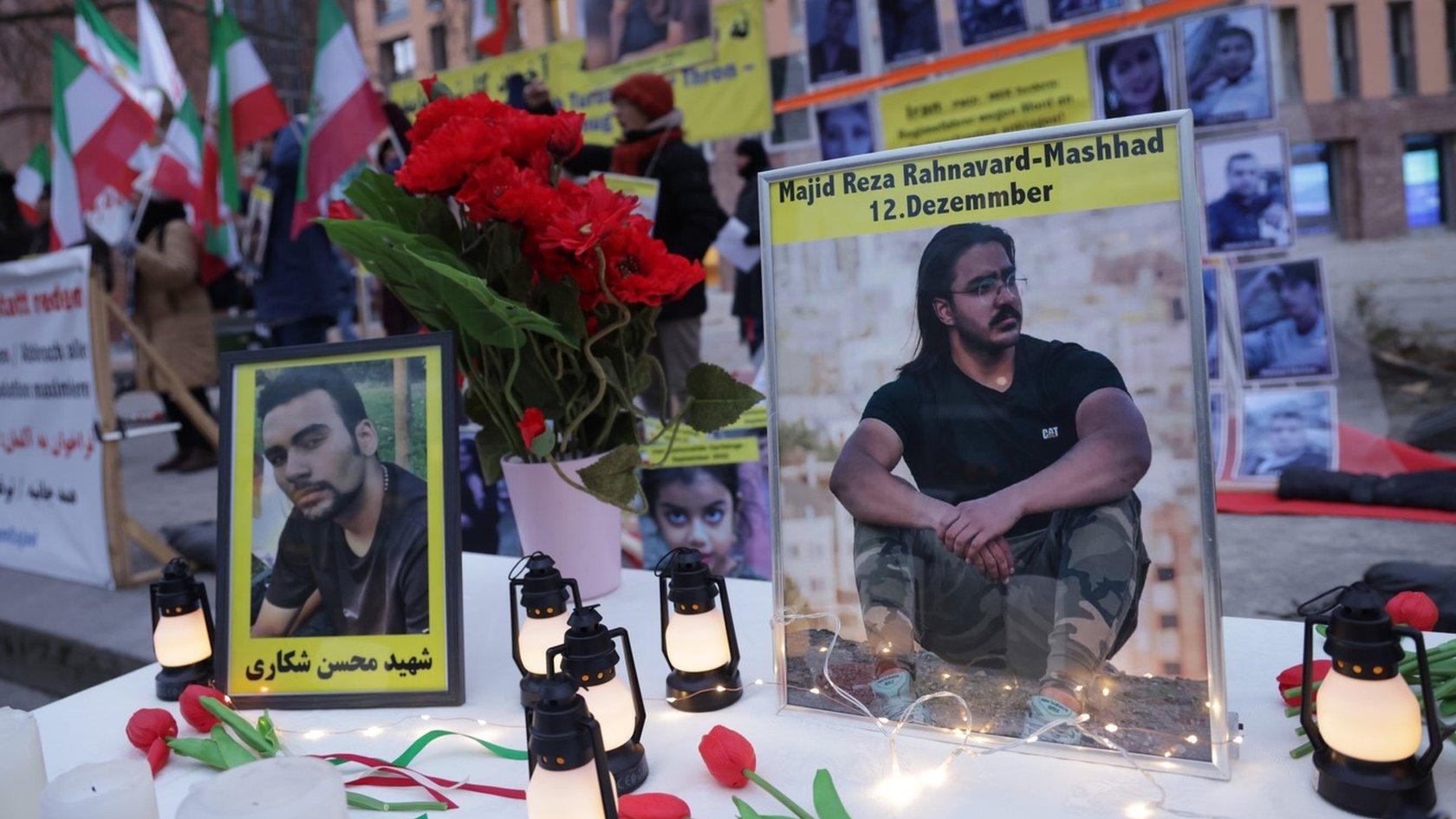 Photos of Mohsen Shekari (L) and Majidreza Rahnavard (R) and stand on a table among candles during a demonstration by an exiled Iranian opposition group outside the German Foreign Ministry in Berlin, Germany (12 December 2022)