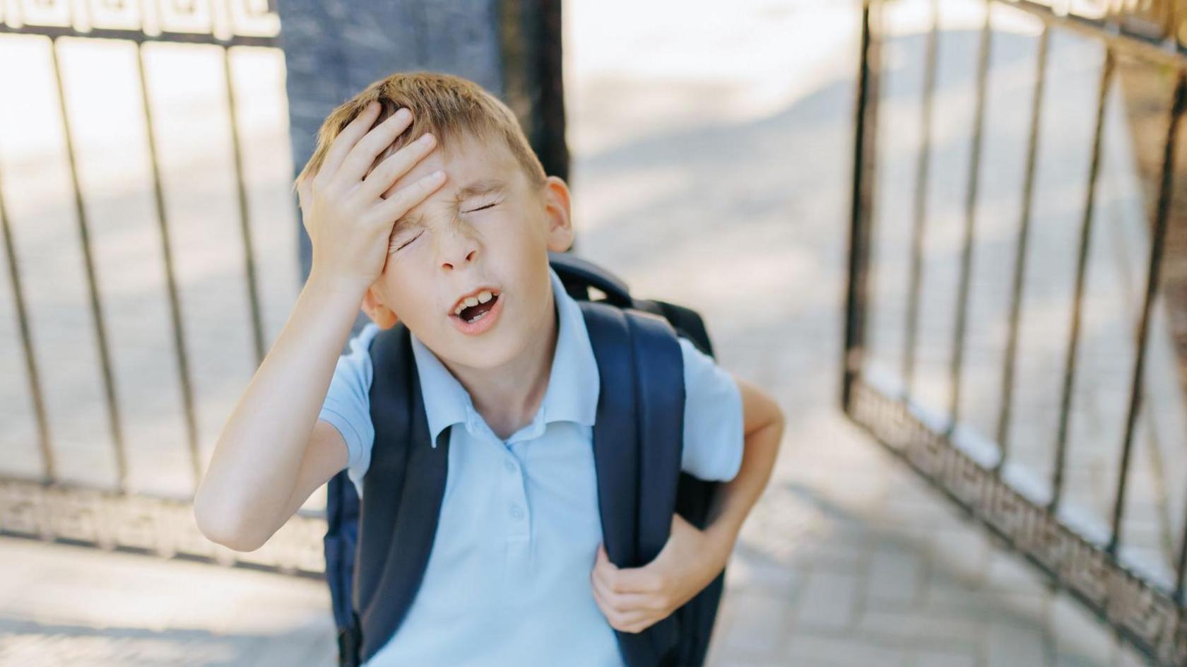 A boy looks hot coming out of school