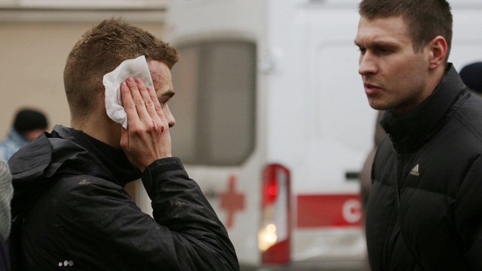 An injured person stands outside Sennaya Ploshchad metro station following explosions in St. Petersburg