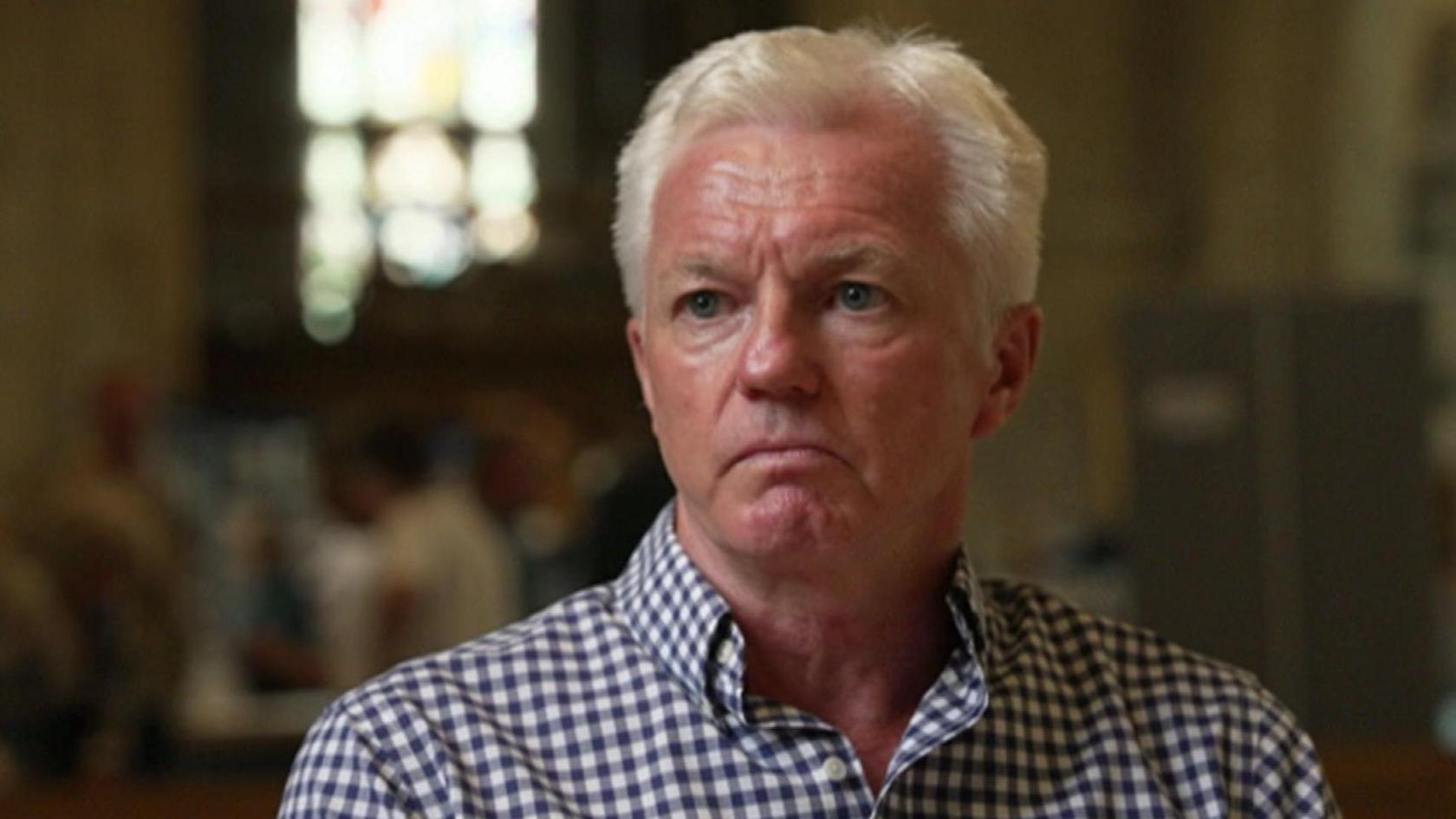 Mark Dunn looks at the camera - he is wearing a blue gingham shirt