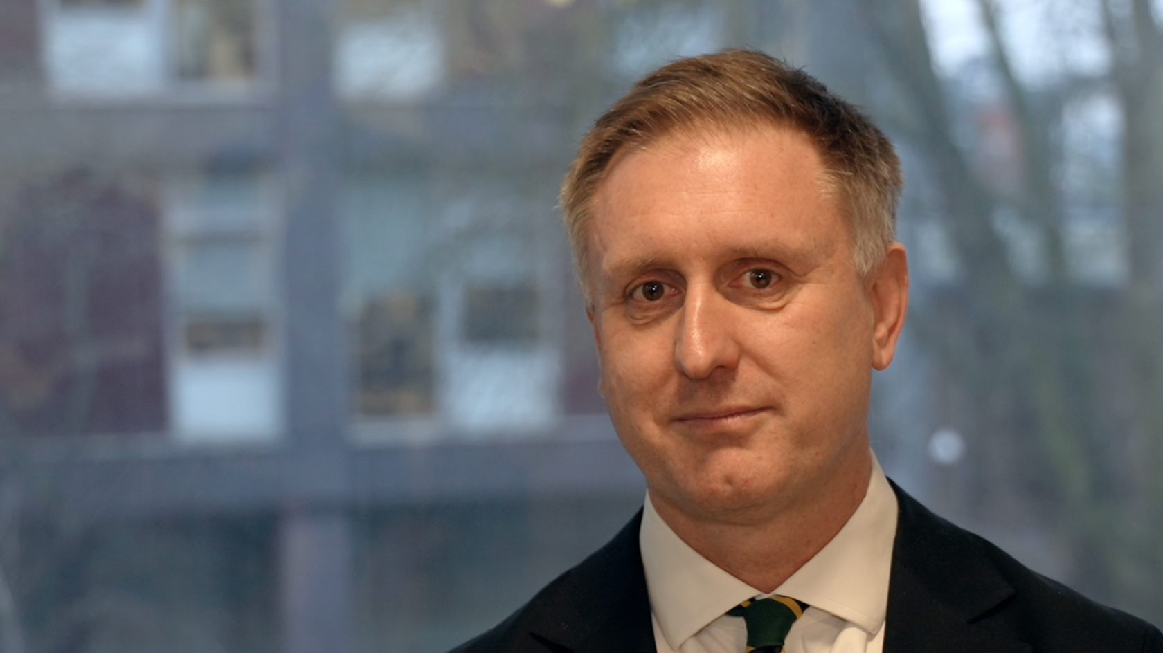 Ed Garrett, a man with short light brown hair wearing a shirt and tie. He is looking into the camera. 