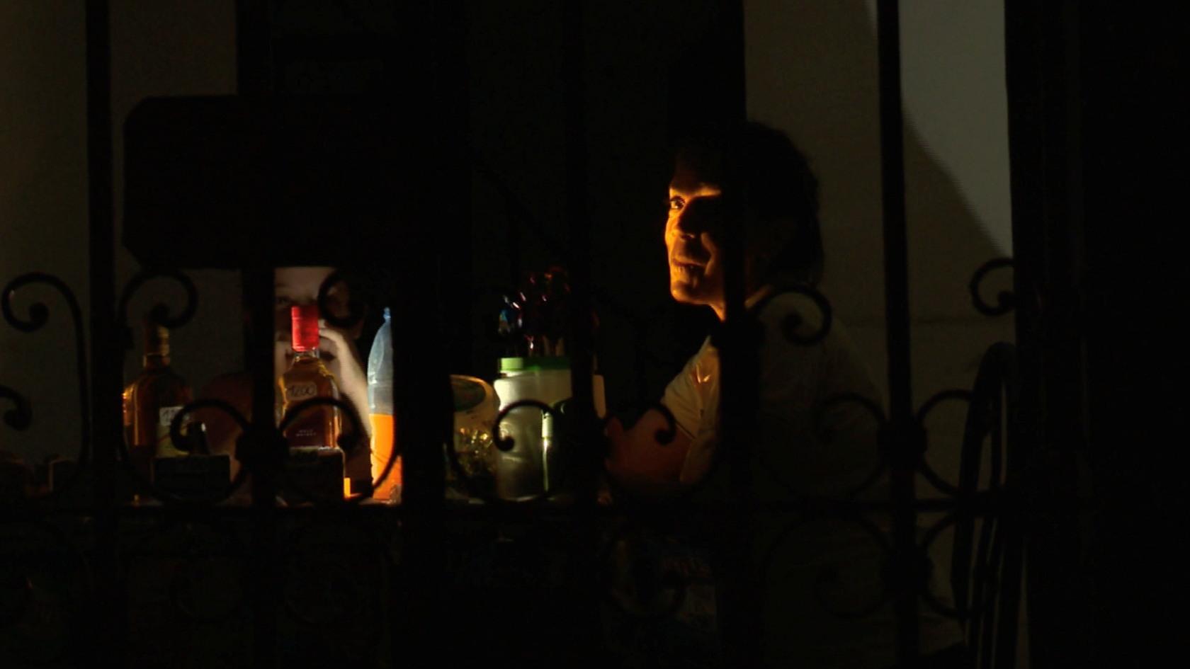 Person sits at a table in the dark, with drinks