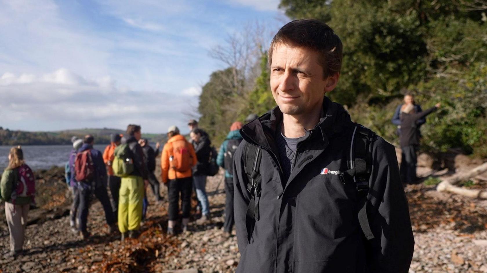 A man looking towards the camera with a large group of people behind him.