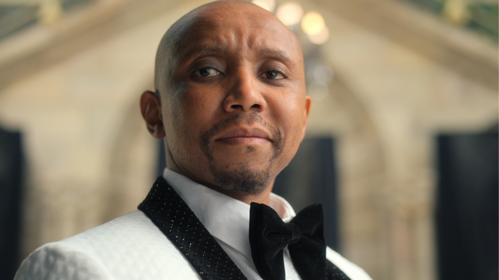 Actor Sdumo Mtshali in a smart white jacket with black diamante collar and large black velvet bow tie.