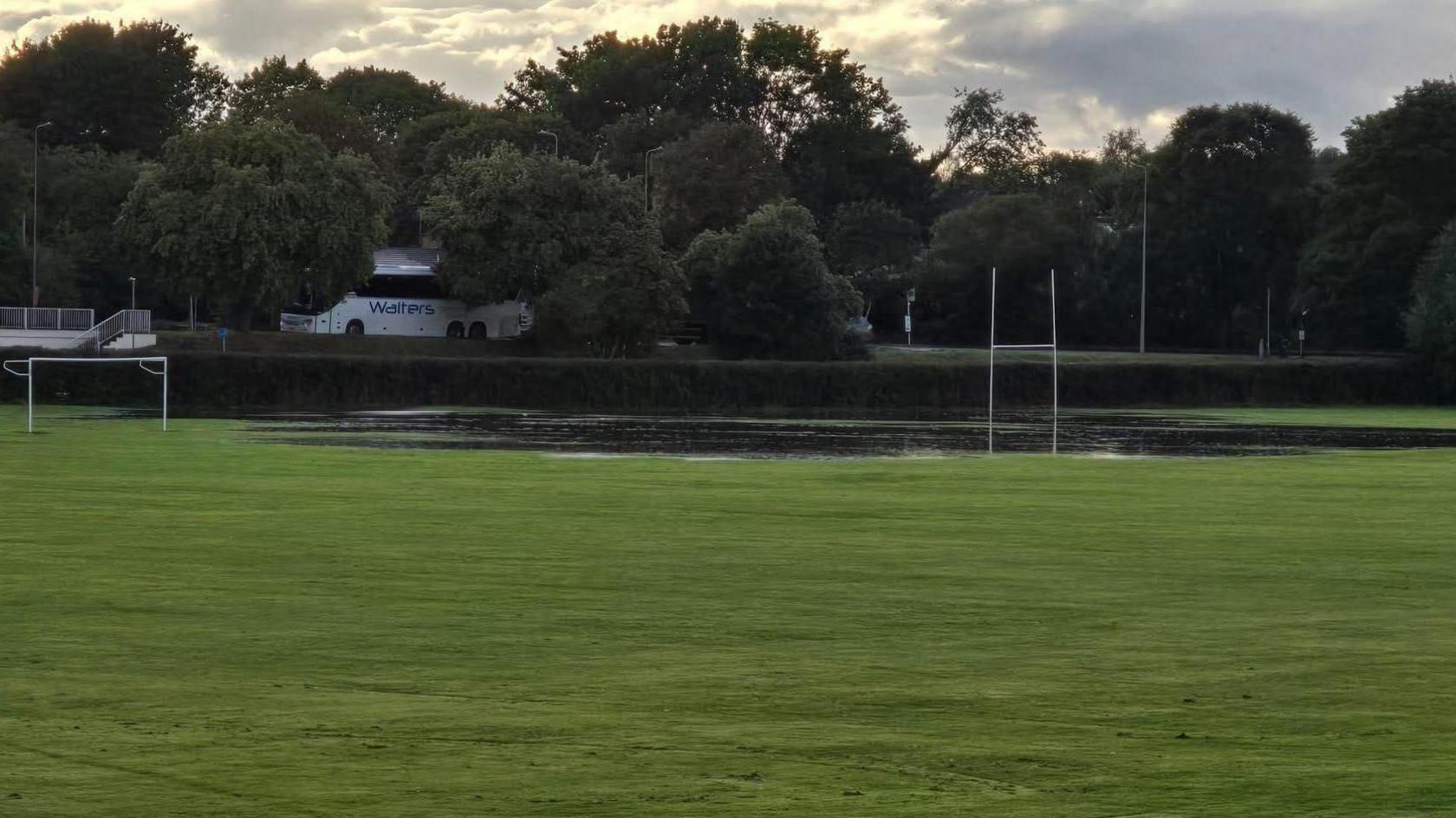 Large green playing field submerged in water along its far edge.