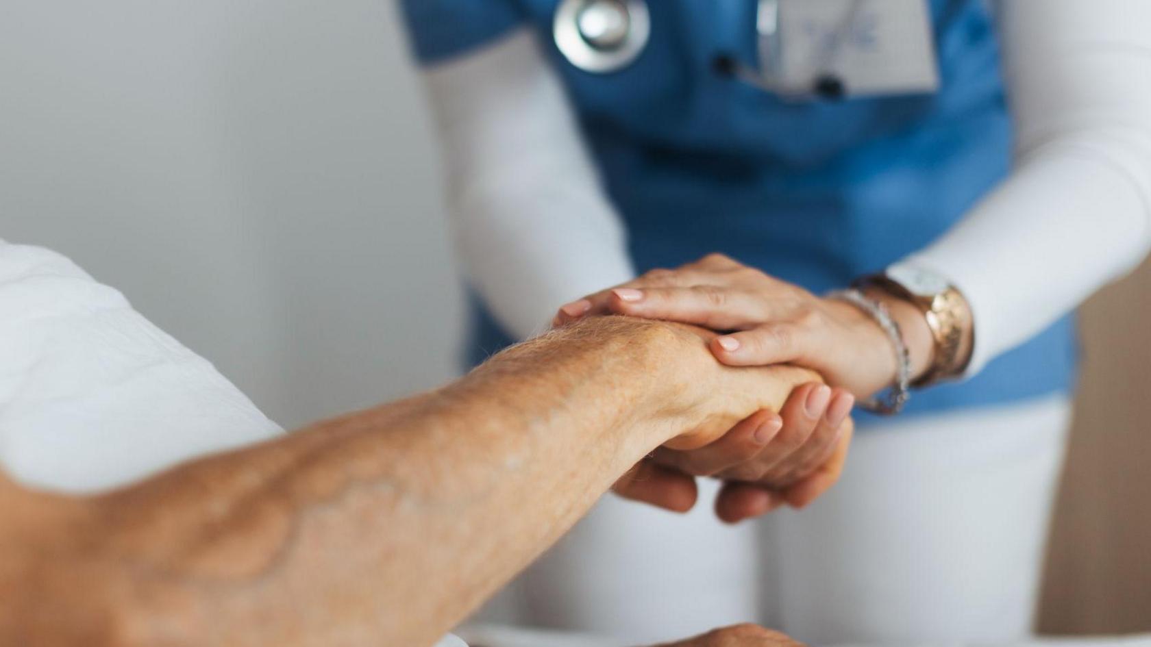 A nurse holding the hand of a patient.