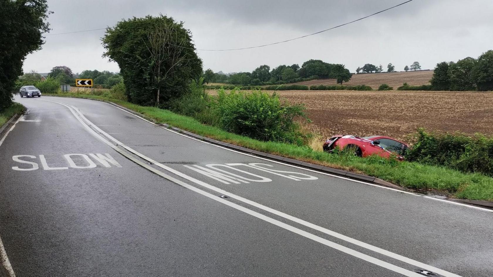 A red car in hedgerow off the A6006