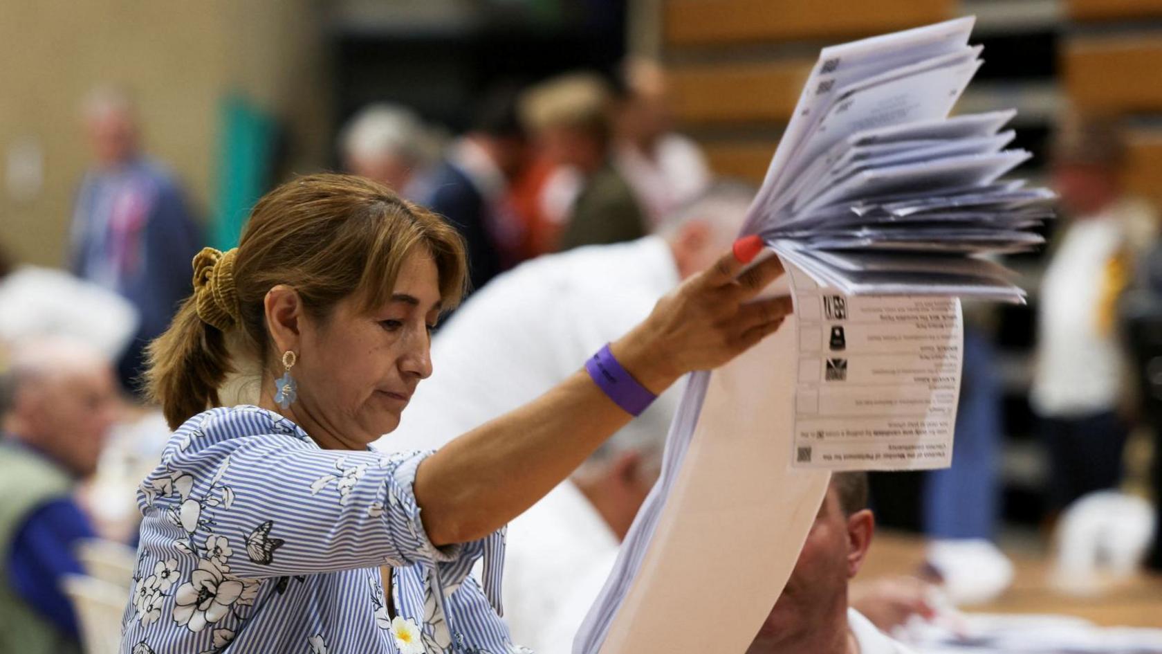 An election worker sorts a pile of ballots during the vote counting for the Clacton by-election.