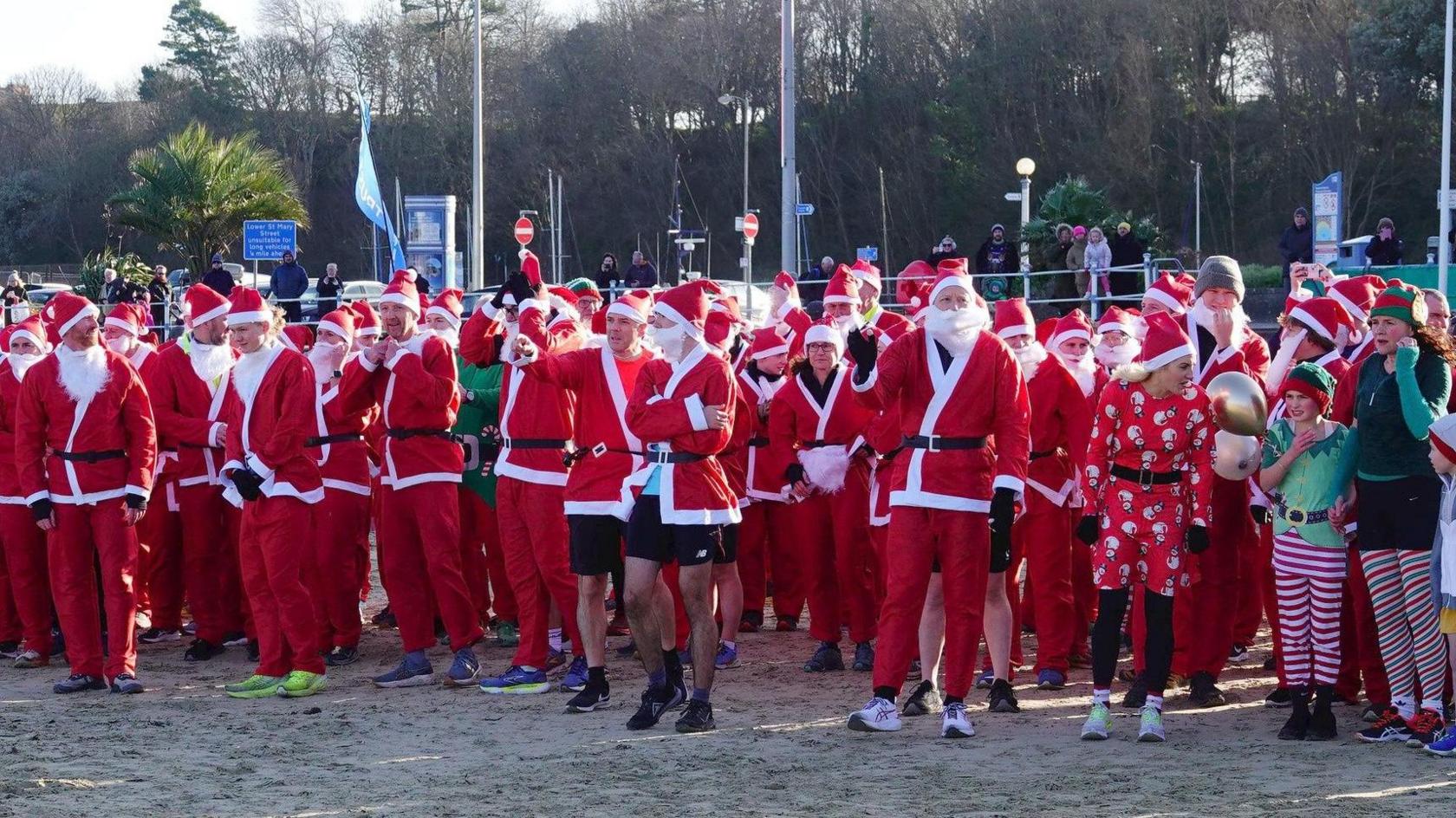 crowds of people dressed as santas on the beach