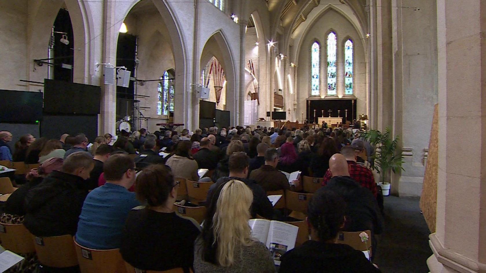 A large group of people gather inside a church for the remembrance service