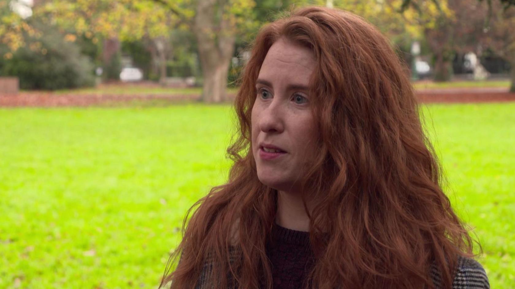 Aoife Moore close up to camera with grass and trees in the background. 