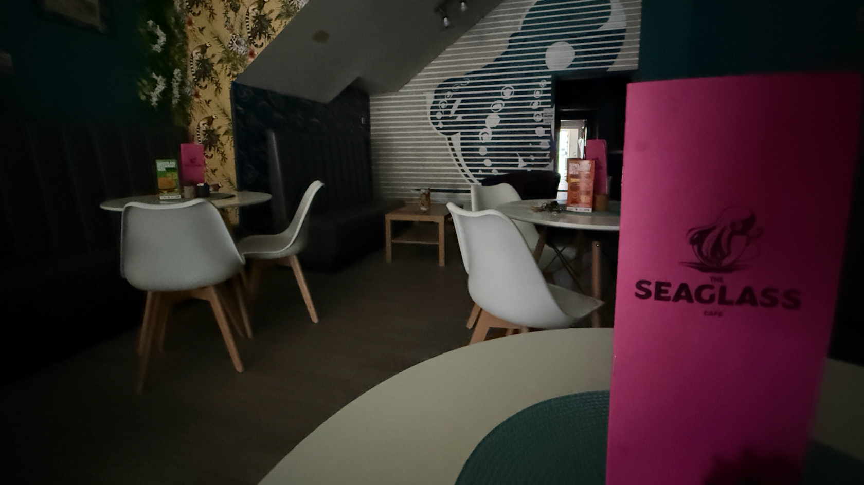 White tables and chairs inside a cafe with all the lights off