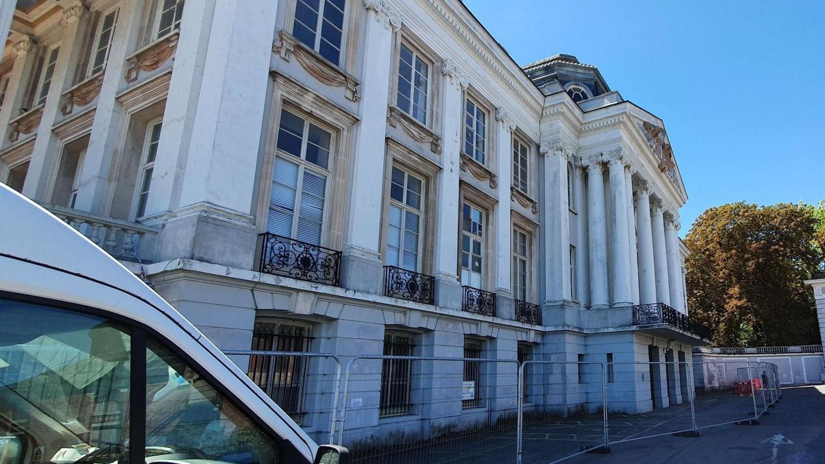 Oldway Mansion from the outside with fencing around it and a white van next to it