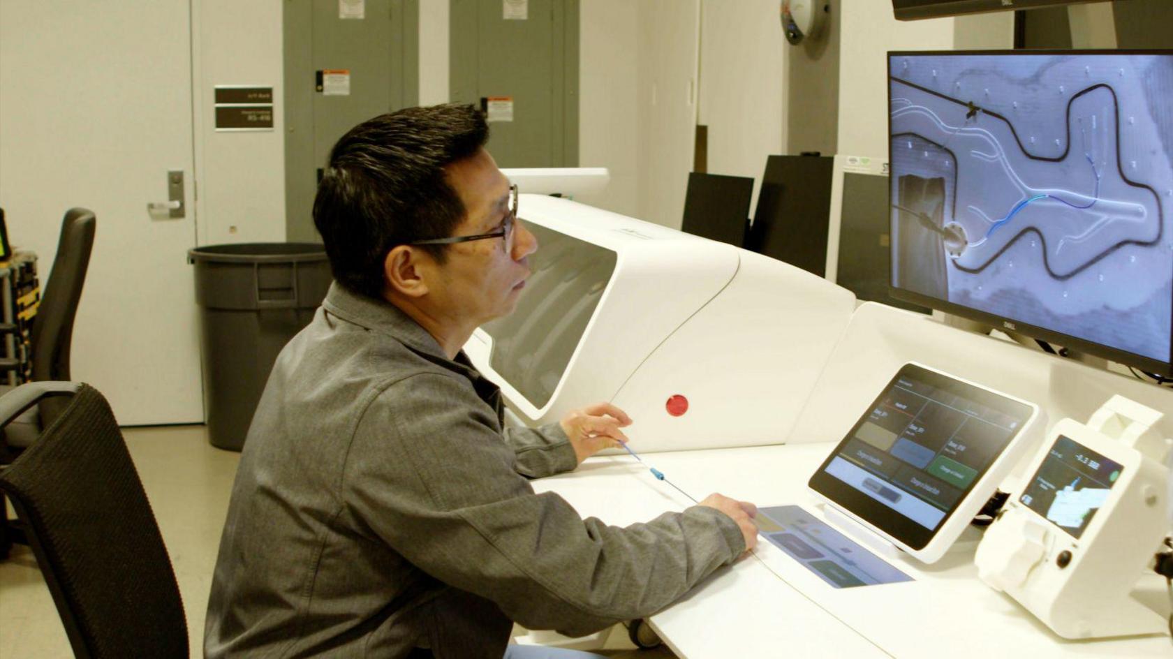 A man sitting in front of a computer looking at a scan.