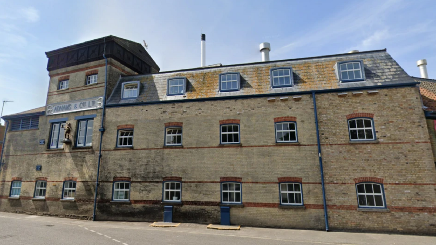 The outside of Adnams' brewery in Southwold. A large brick three-storey building with sash windows. It has a sign reading "Adnams & Co Ltd". 