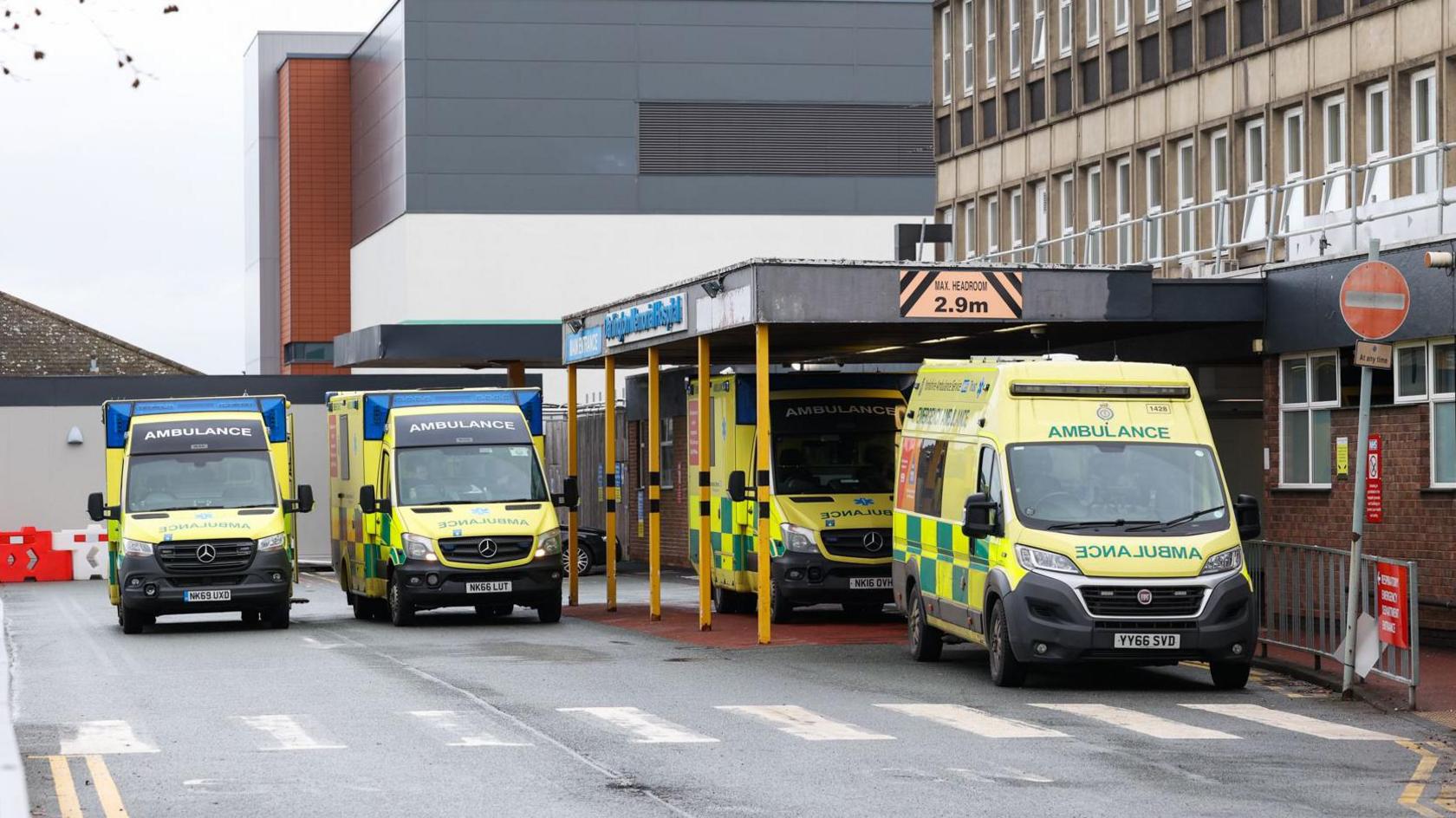 Four ambulances outside a brown hospital building