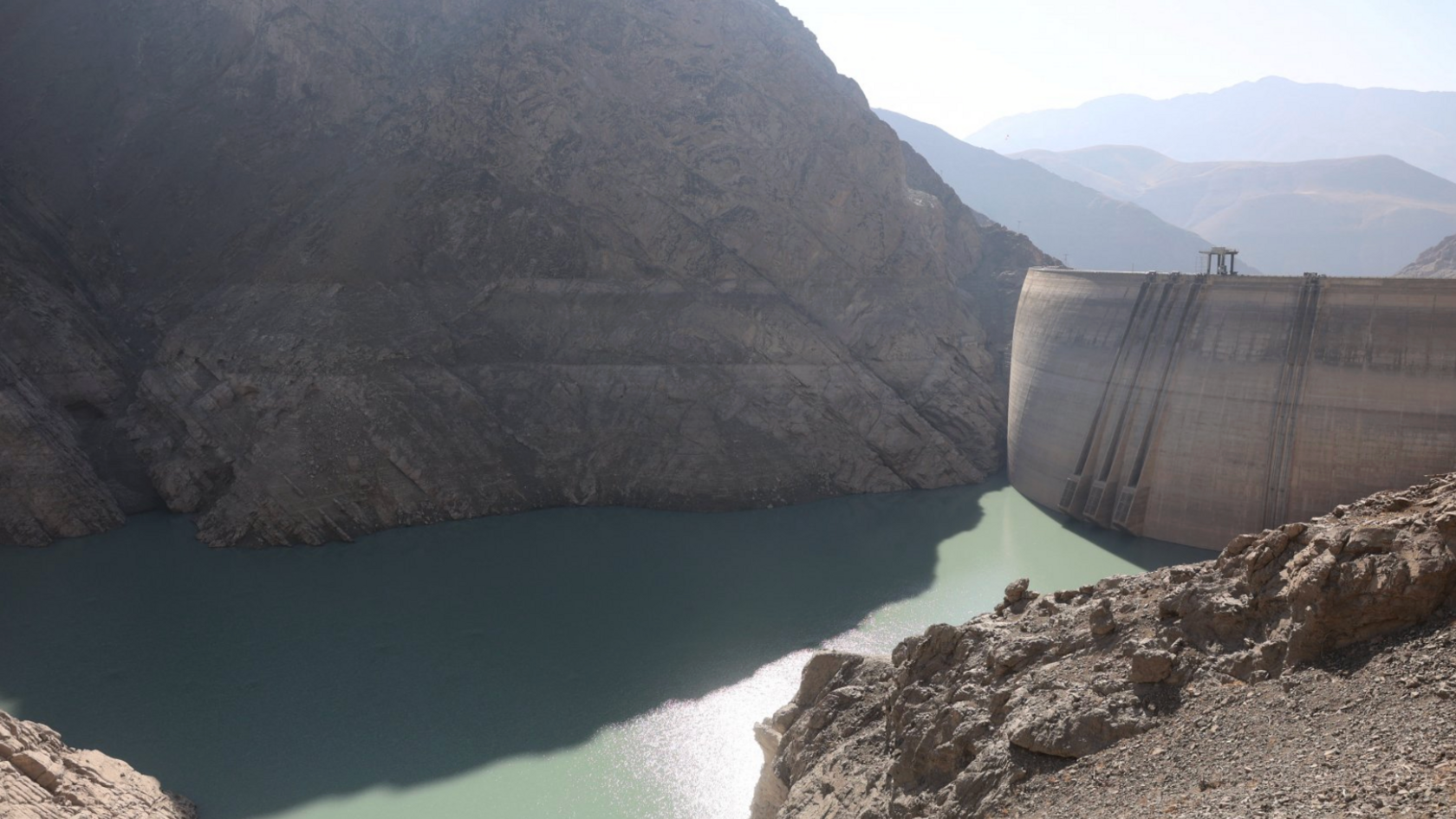 The Amirkabir dam. Green coloured water can be seen in front of a rockface.