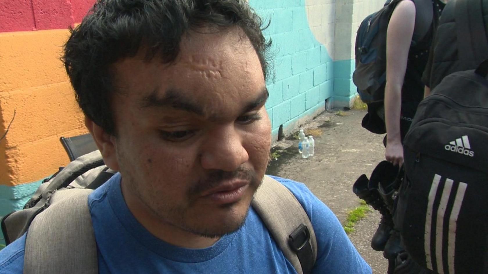 Latif Lewis in a blue t-shirt with a ruck sack straps over his shoulders