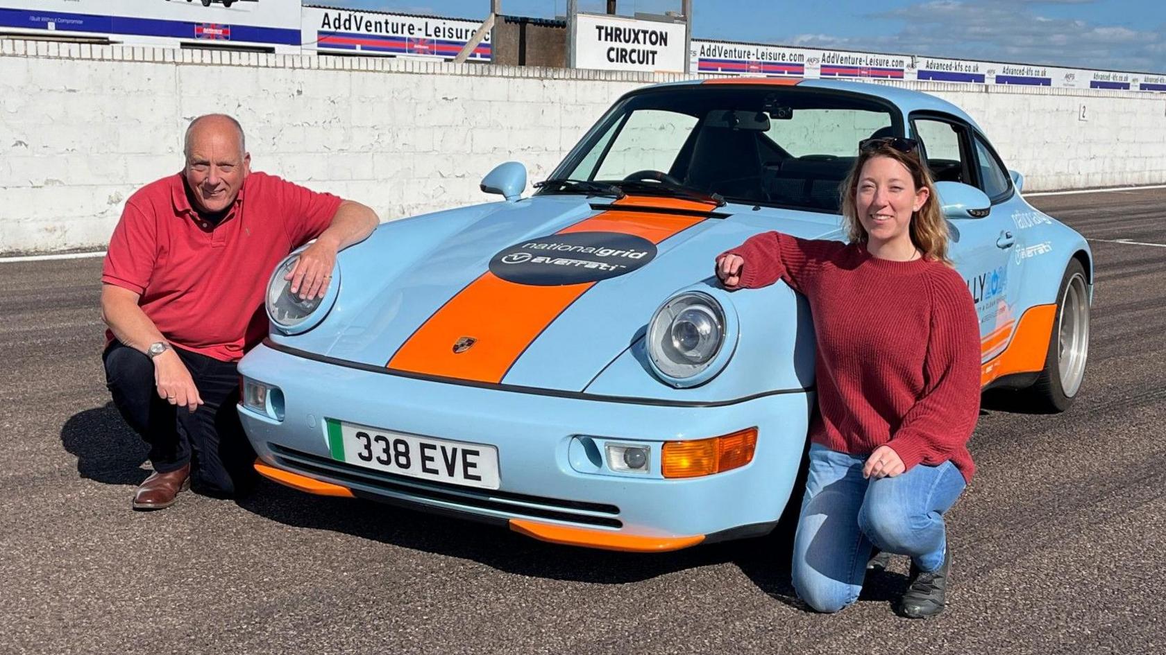 Paul Clifton and his daughter Frankie kneel on either side of the Porsche at Thruxton race track