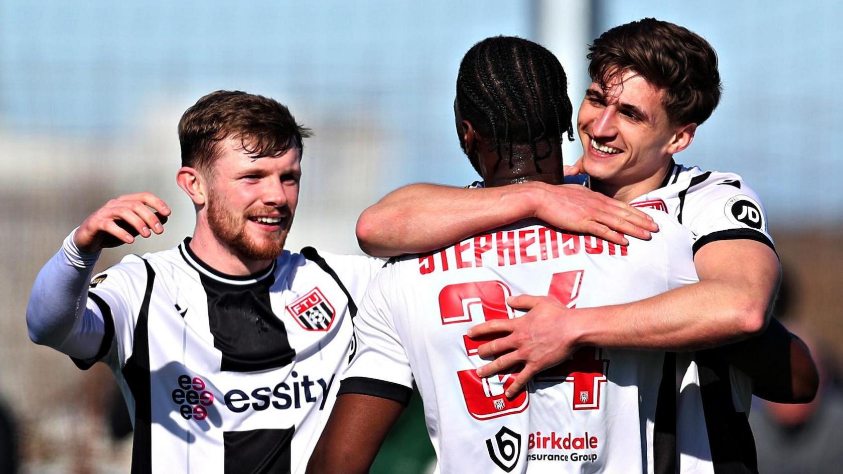 Flint's Elliot Reeves hugs smiling team-mates in celebration after scoring his second goal in the semi-final