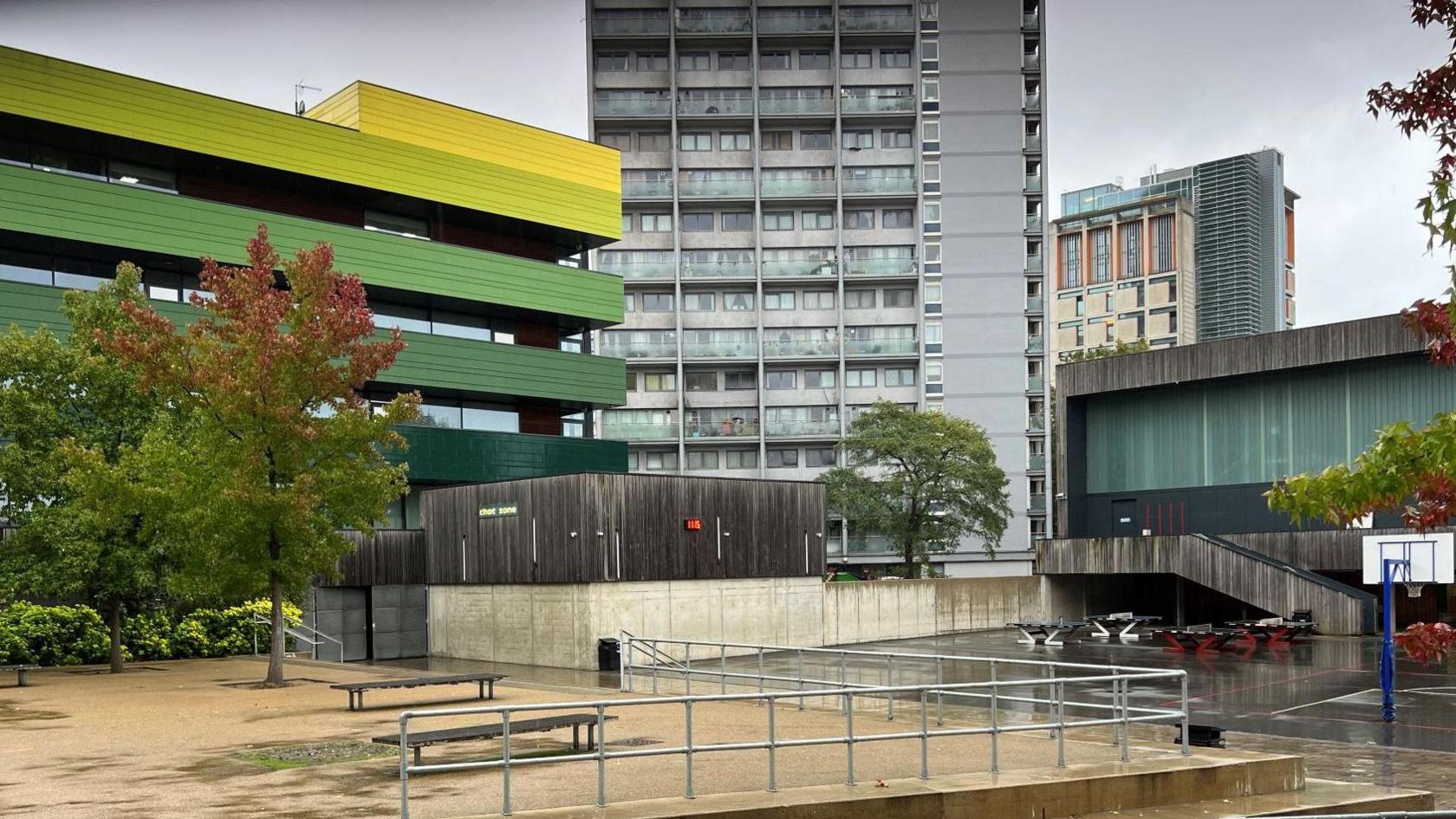 Exterior image of the school, with playground and tower block also in shot