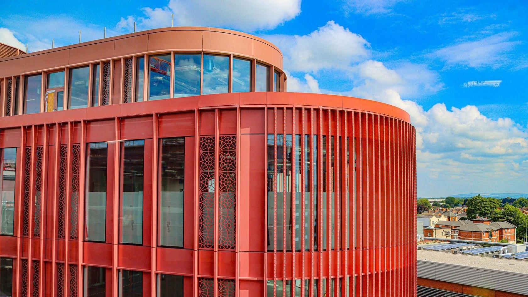 The top two stories of the development, showcasing the red panelling and curved frontage. 