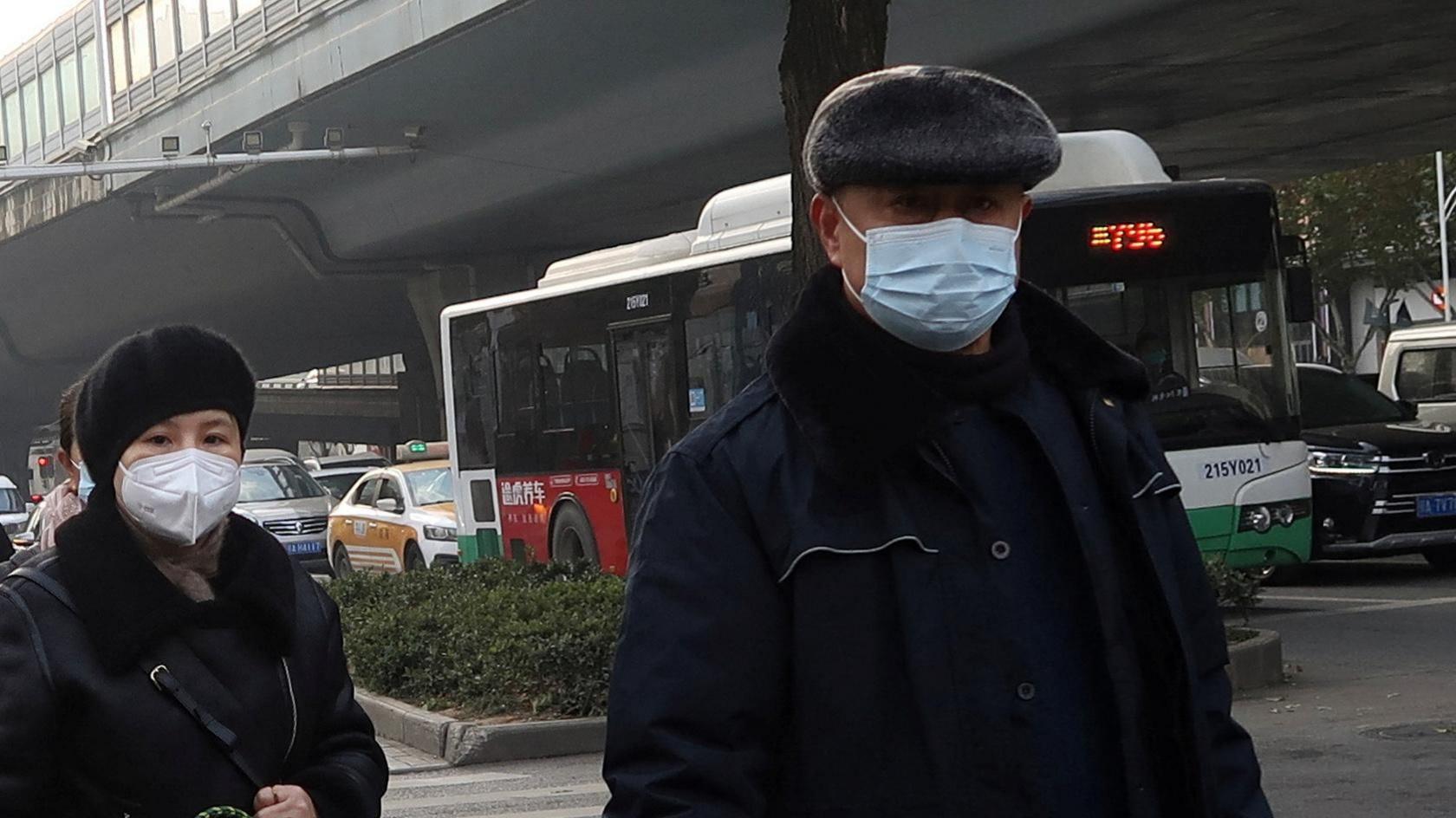 A Chinese man and woman wearing facemasks cross the street in Wuhan during the Covid pandemic