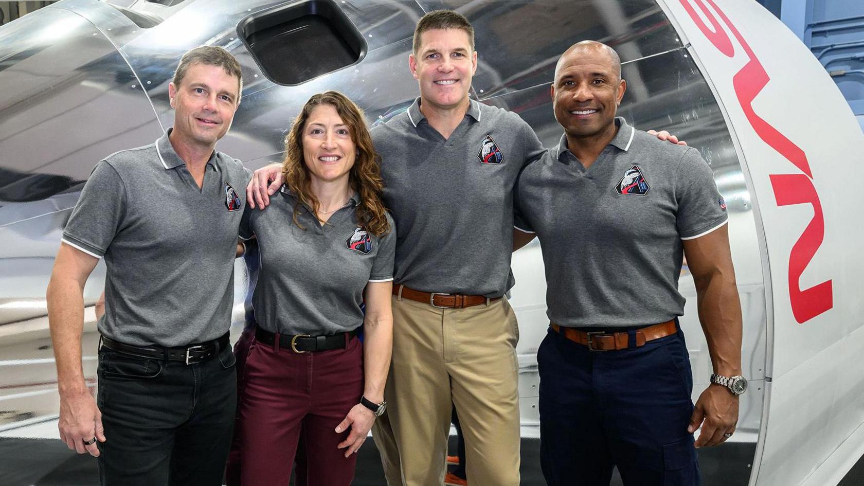 The Artemis II crew pose in front of an Orion simulator at NASA's Johnson Space Centre in Houston. (L-R) Reid Wiseman, Christina Koch, Jeremy Hansen, Victor Glover. They are all wearing a grey polo shirt with the Artemis II mission logo on the breast 