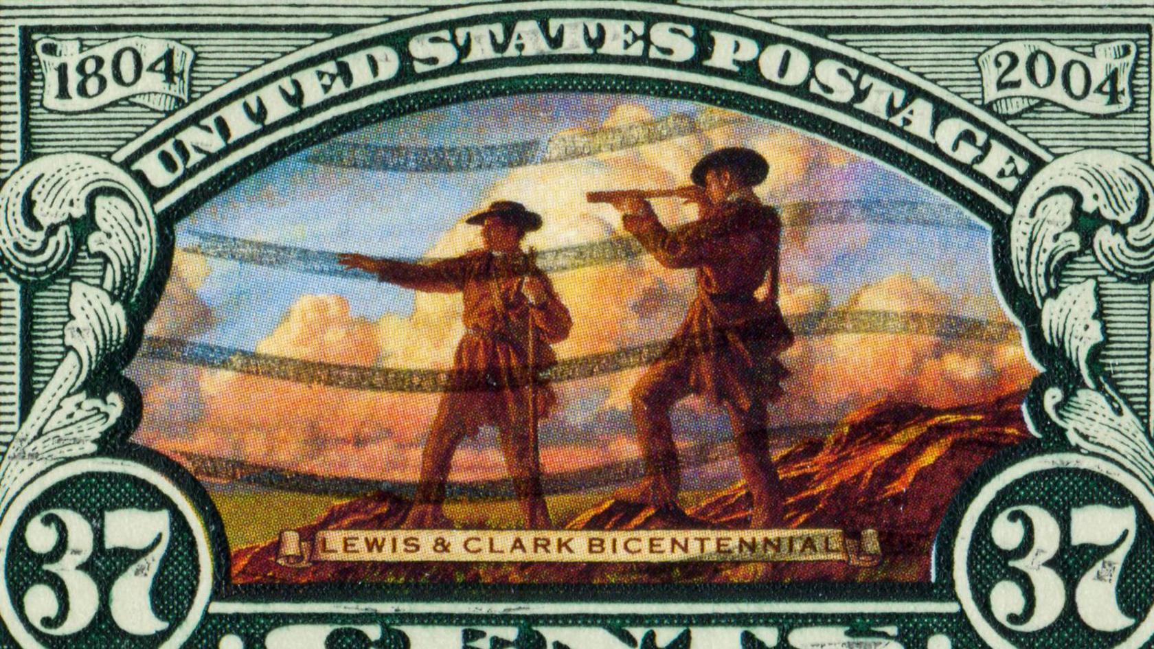 A used 37 cent stamp showing the explorers Meriwether Lewis and William Clark, one with a telescope and the other pointing into the distance. Large white clouds are behind them as they stand on a rocky lookout