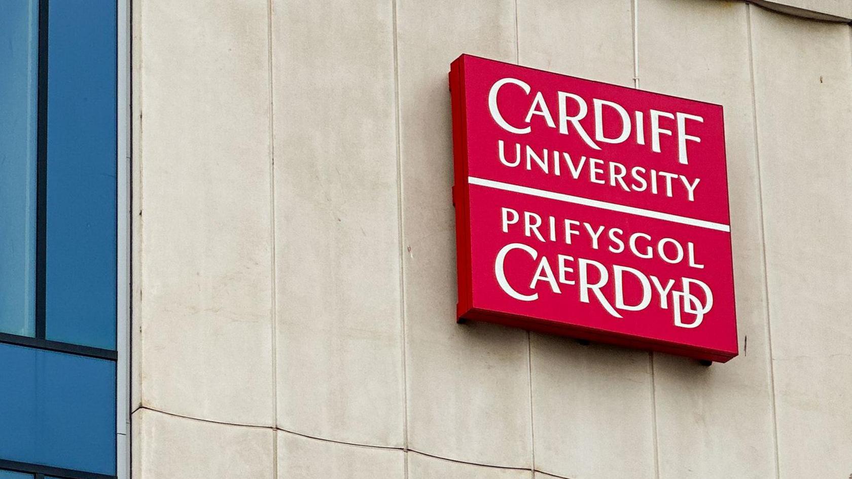 Un o adeiladau'r brifysgol gyda arwydd coch yn dweud Prifysgol Caerdydd a Cardiff University
