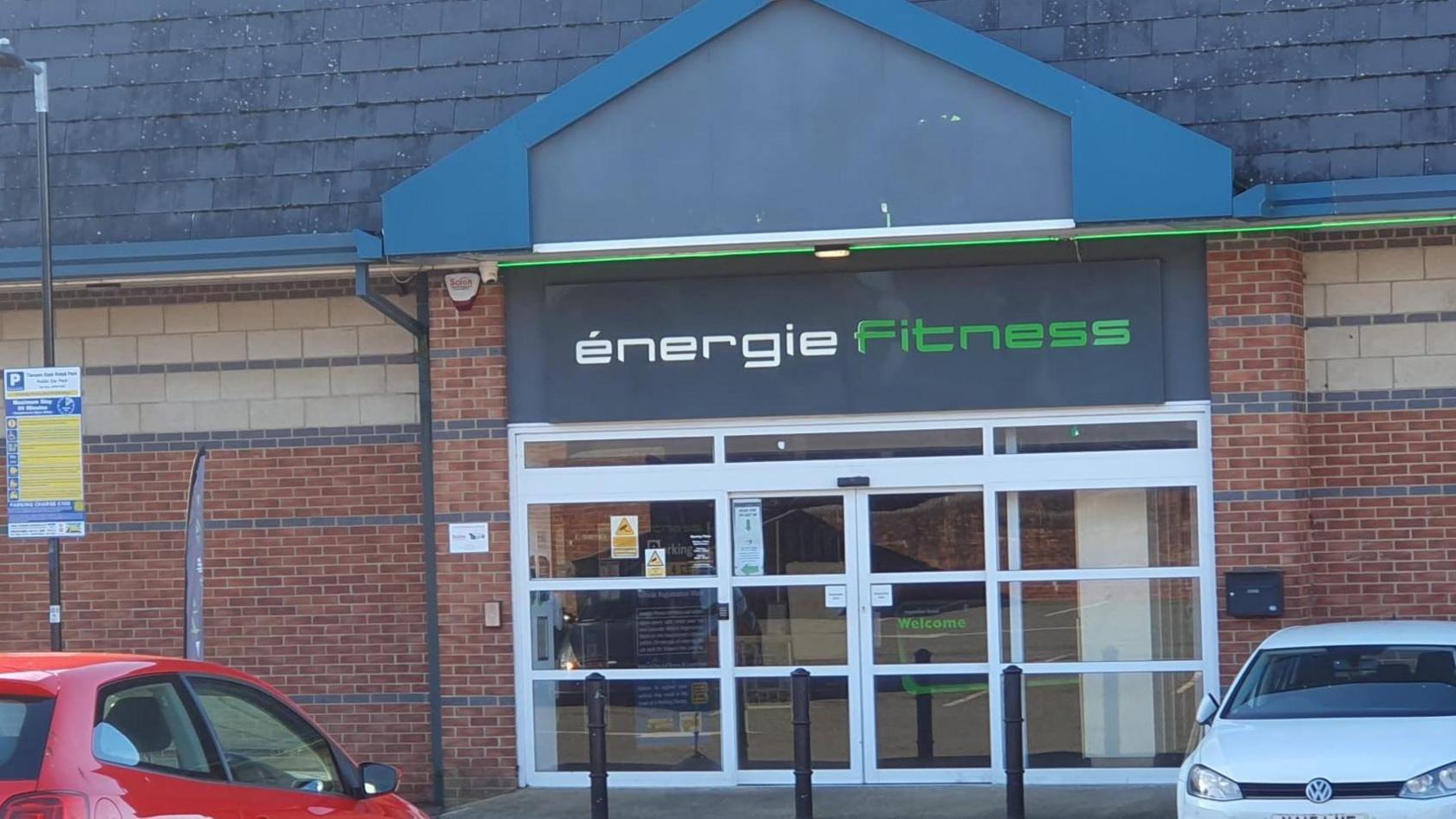 The front of a gym - glass door frontage with a black sign saying "Energie Fitness" 