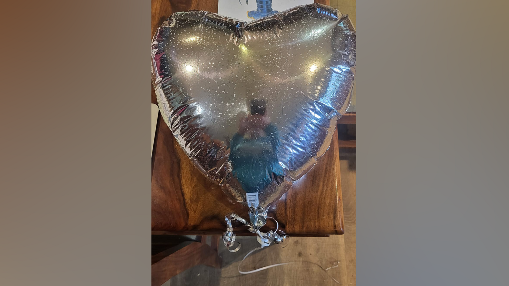 A silver foil balloon in the shape of a heart.