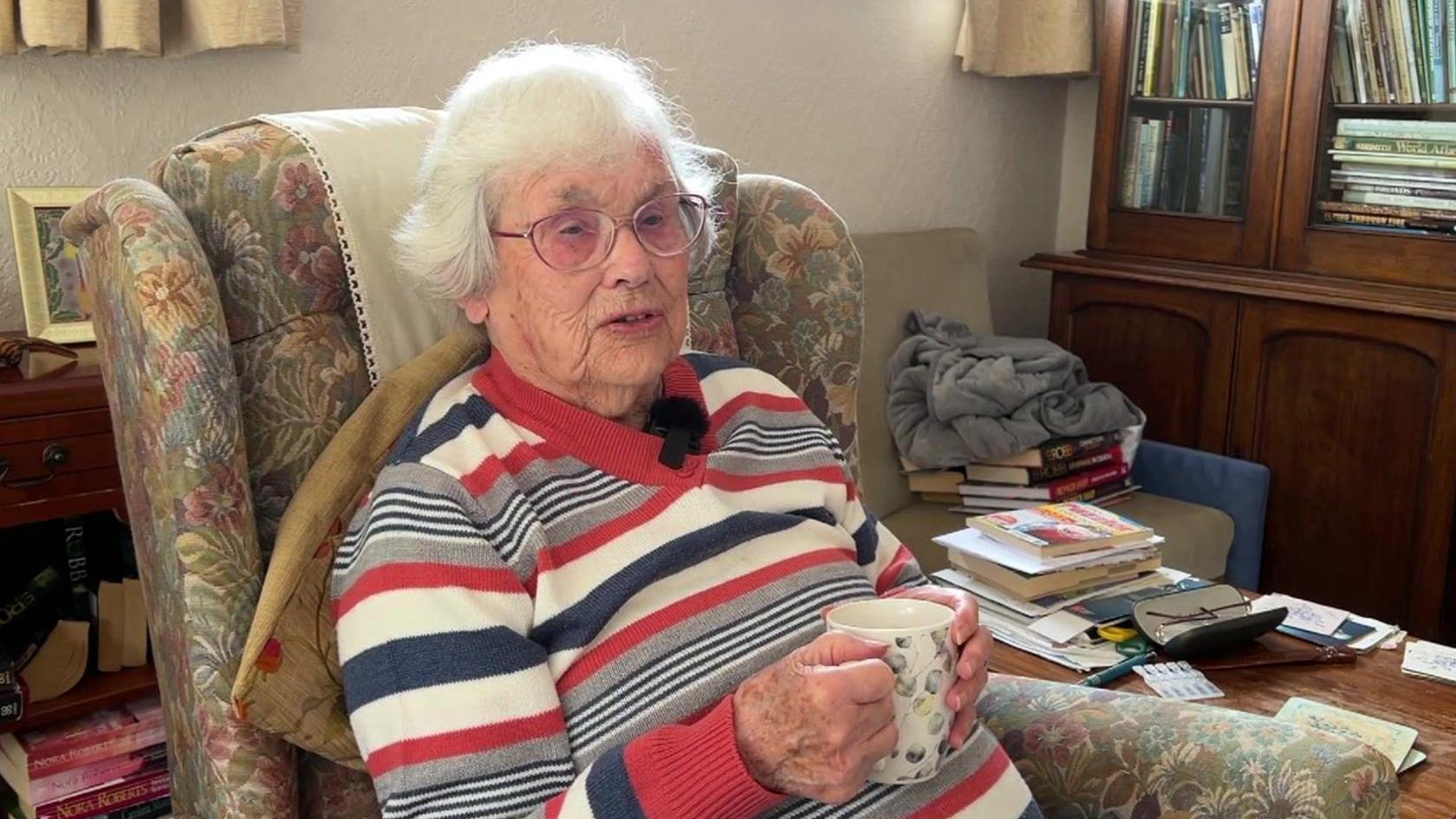 Myrtle Feek, an older woman holding a cup of tea