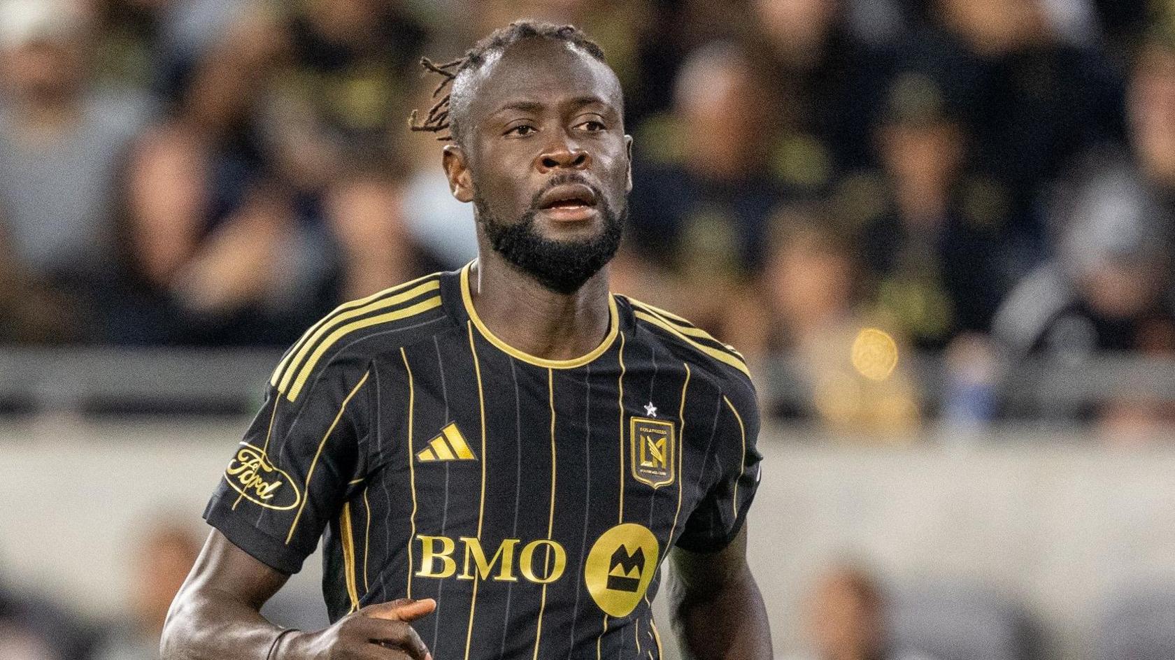 Kei Kamara pictured wearing a black LA FC shirt with gold pinstripes and detailing