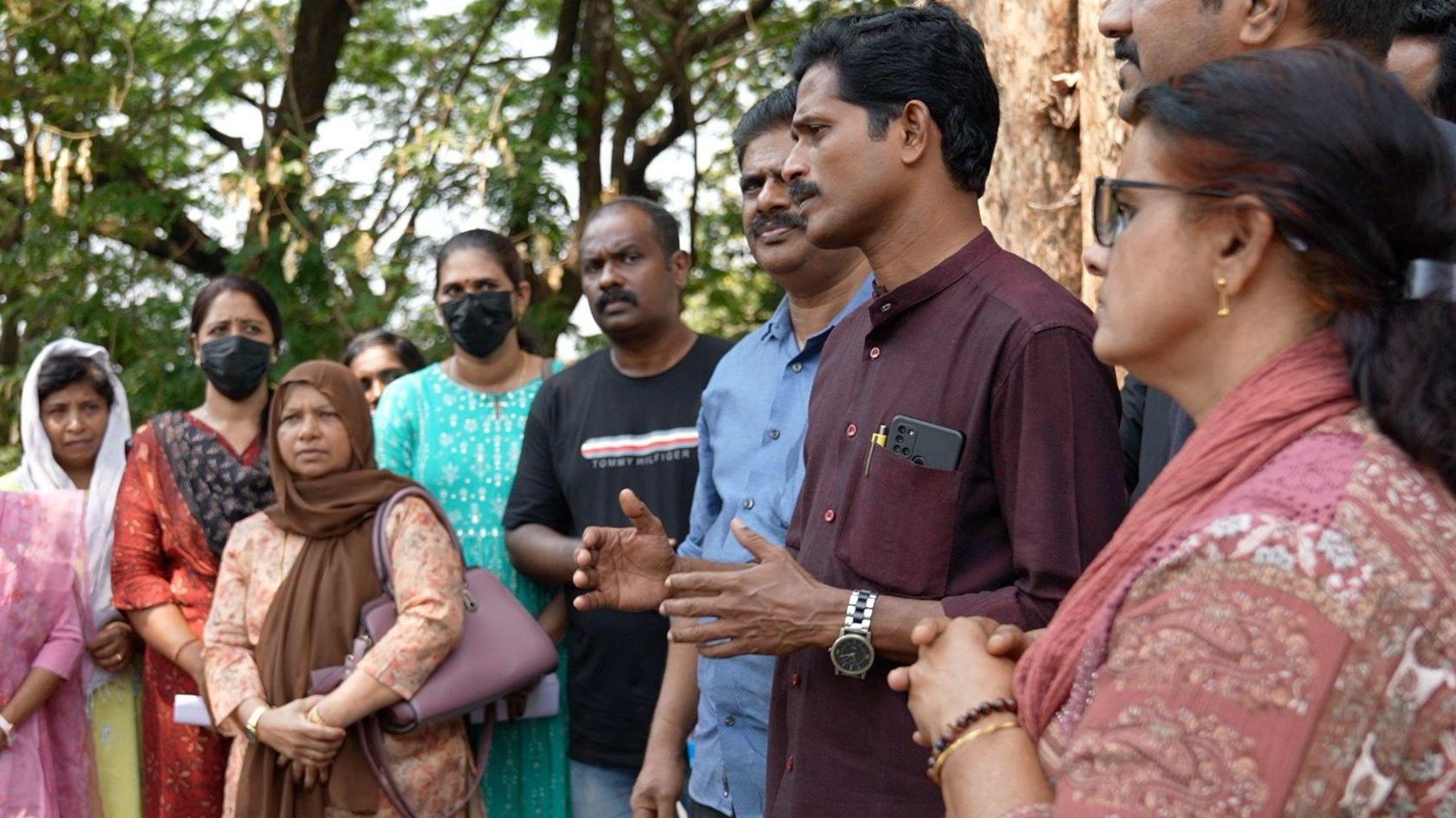 The image shows a men and women care workers in Kothamangalam town in Kerala, talking about the millions they lost while trying to obtain a care visa. 