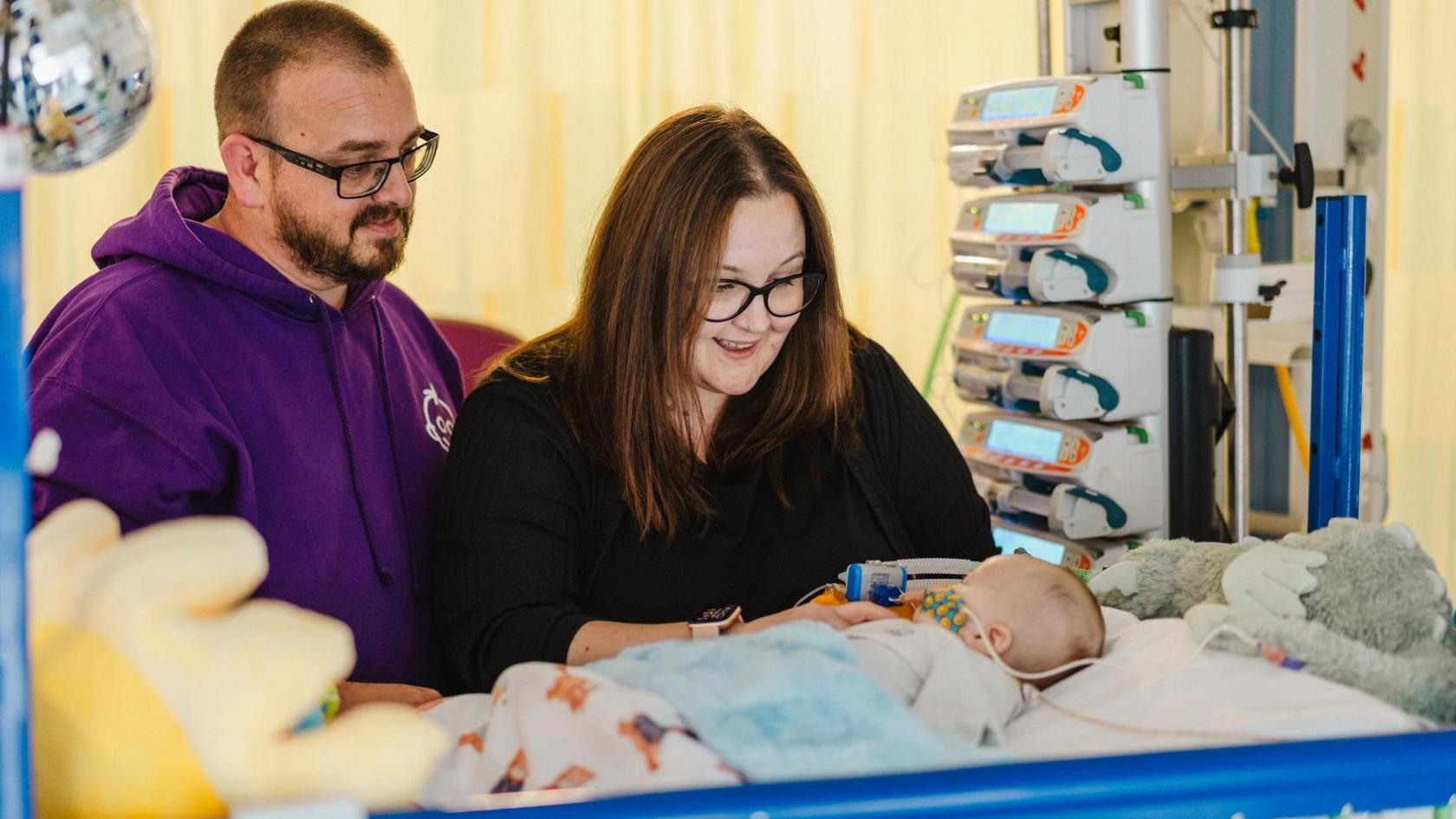 Stuart Jones in a purple hoodie and Laura Osborne in a black top sit by William in an incubator