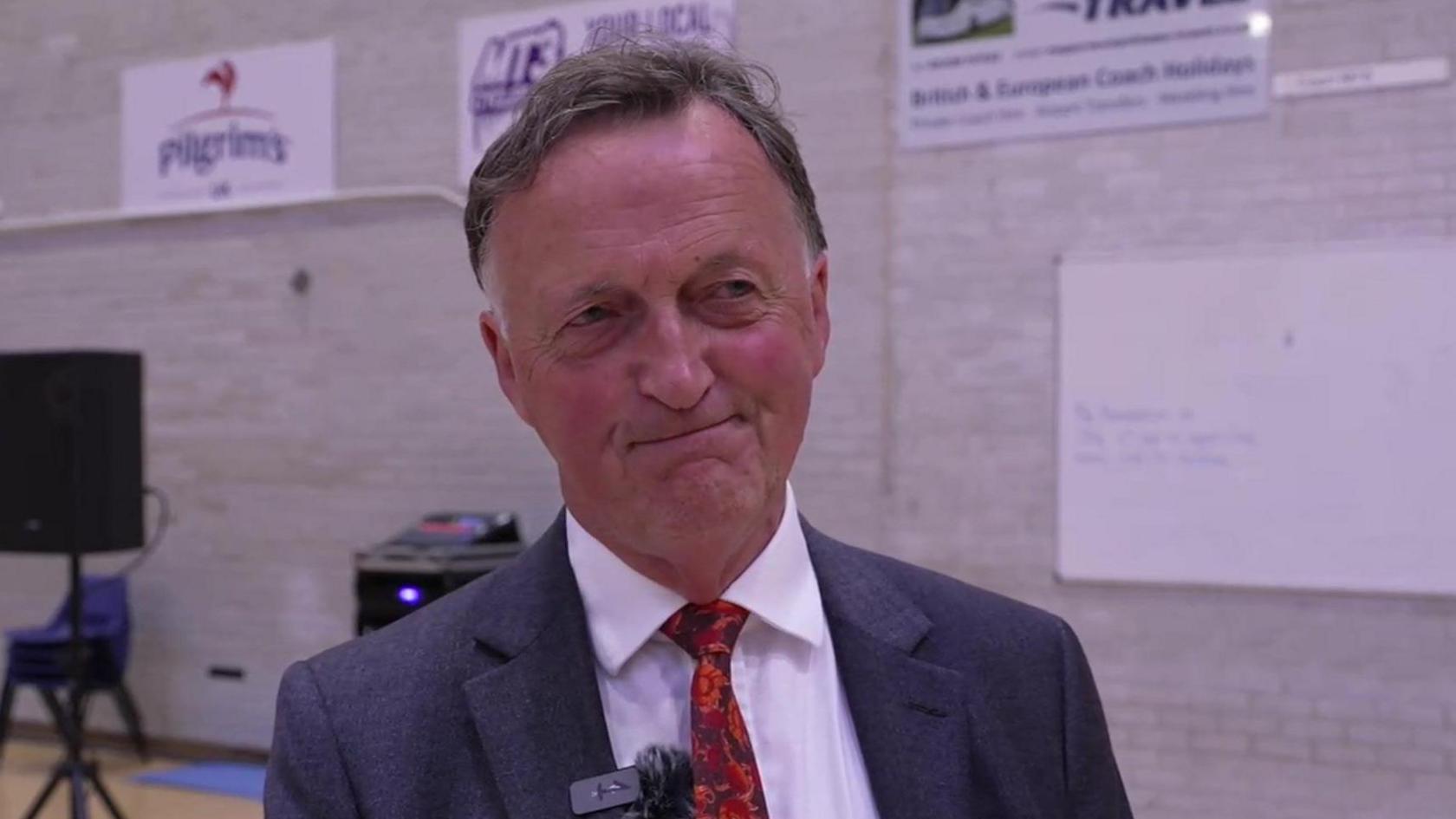 Andrew George, Liberal Democrat MP for St Ives. He is wearing a white suit shirt with a red patterned tie and a black blazer.