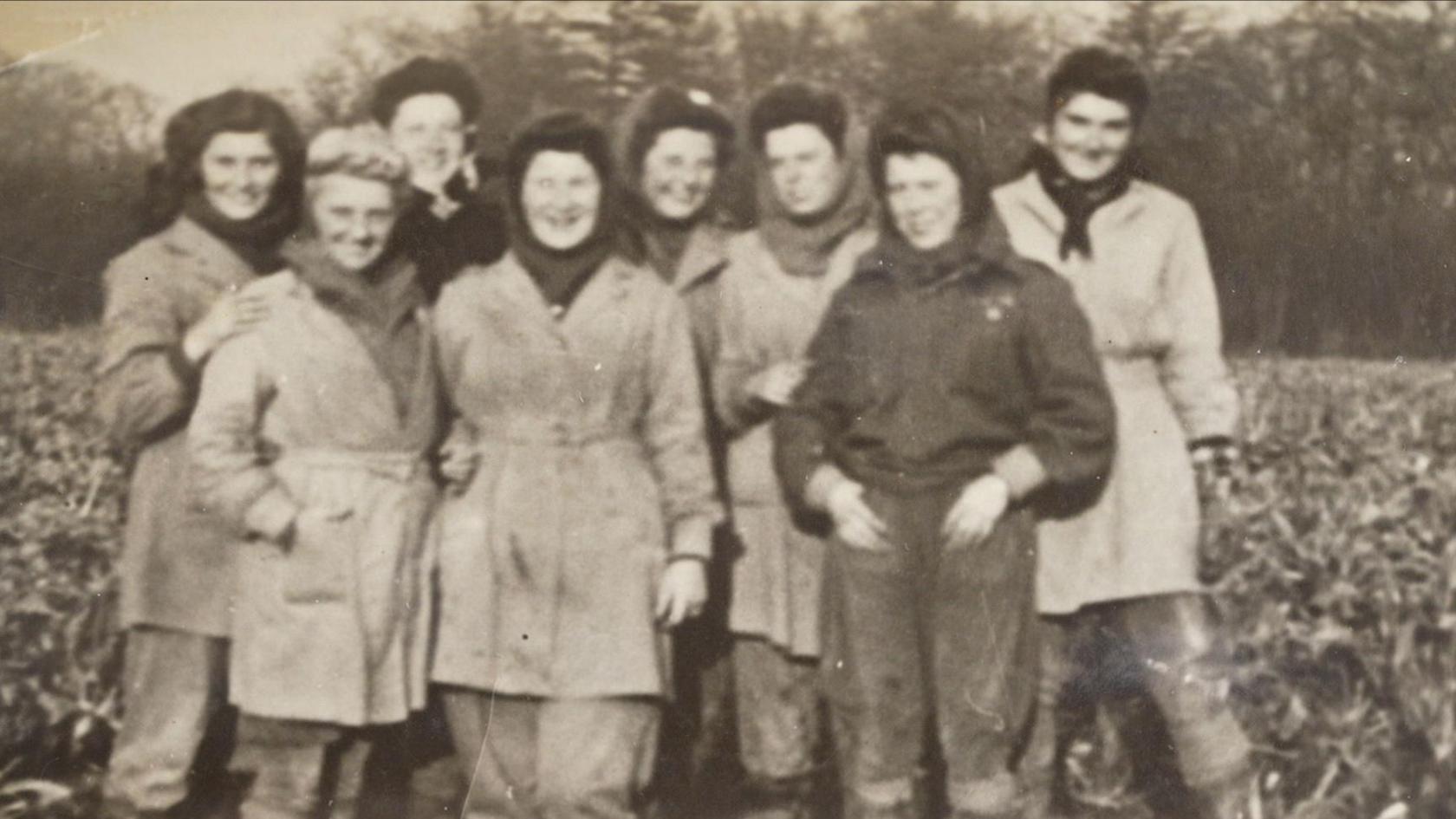 Black and white team photo of eight young women standing together in a field in Essex.
