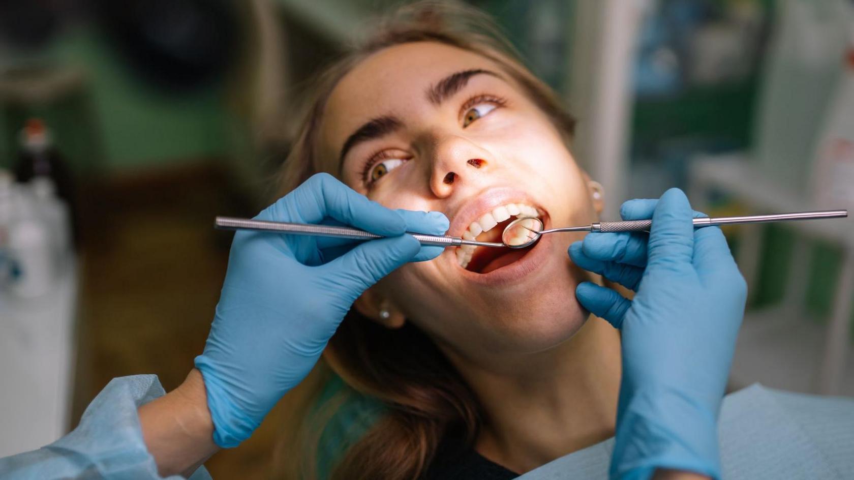 female patient lying in dental chair with mouth open during treatment