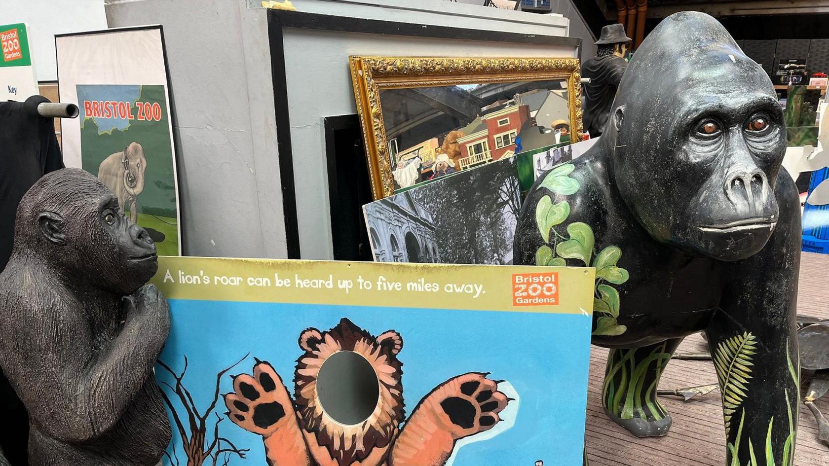 Two gorilla replicas, one large and one small, are seen amid posters and other items being sold off as part of Bristol Zoo's sale of old artwork and other items